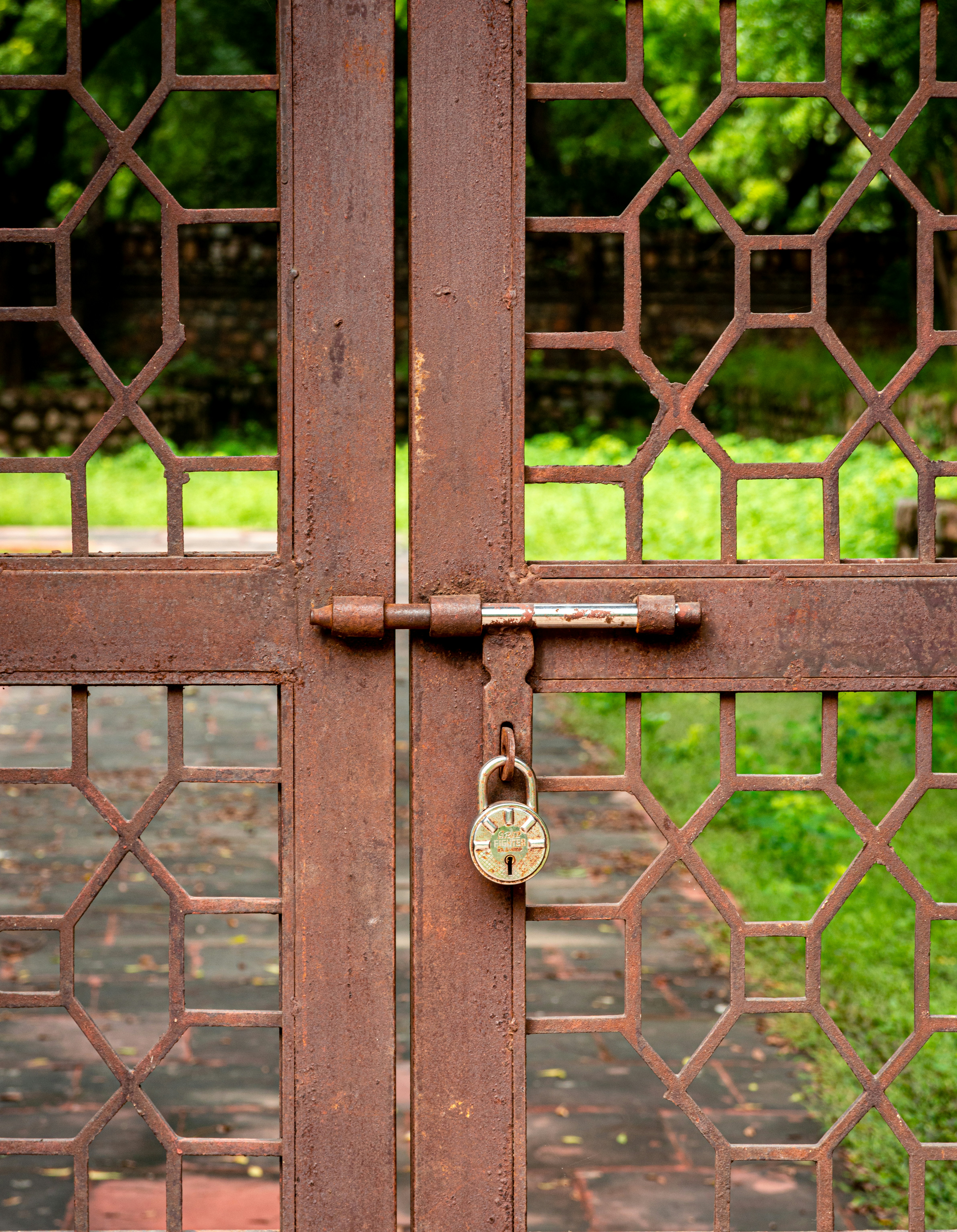 Rusty metal gate with padlock and geometric pattern