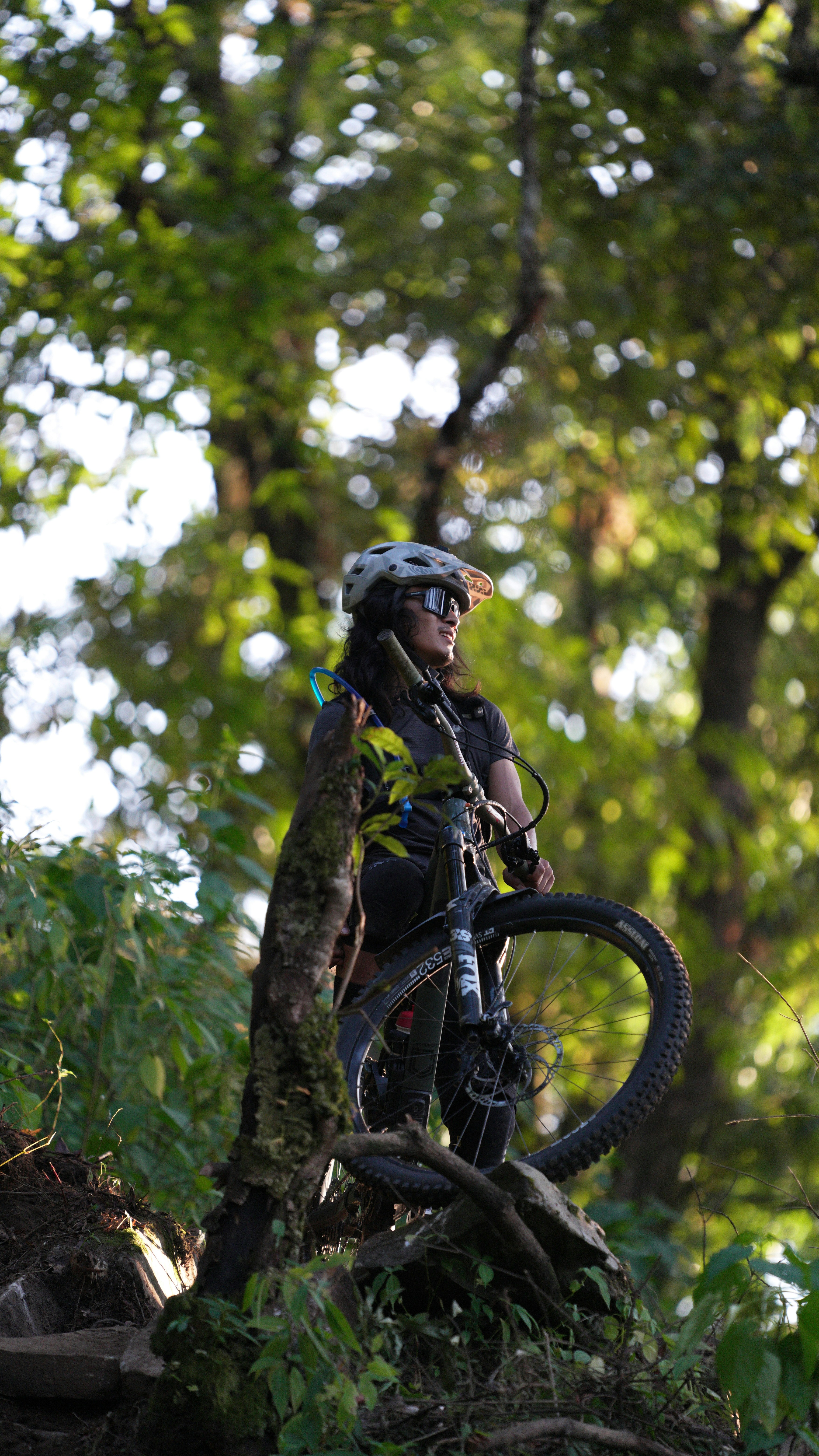 Woman with mountain bike in lush green forest.