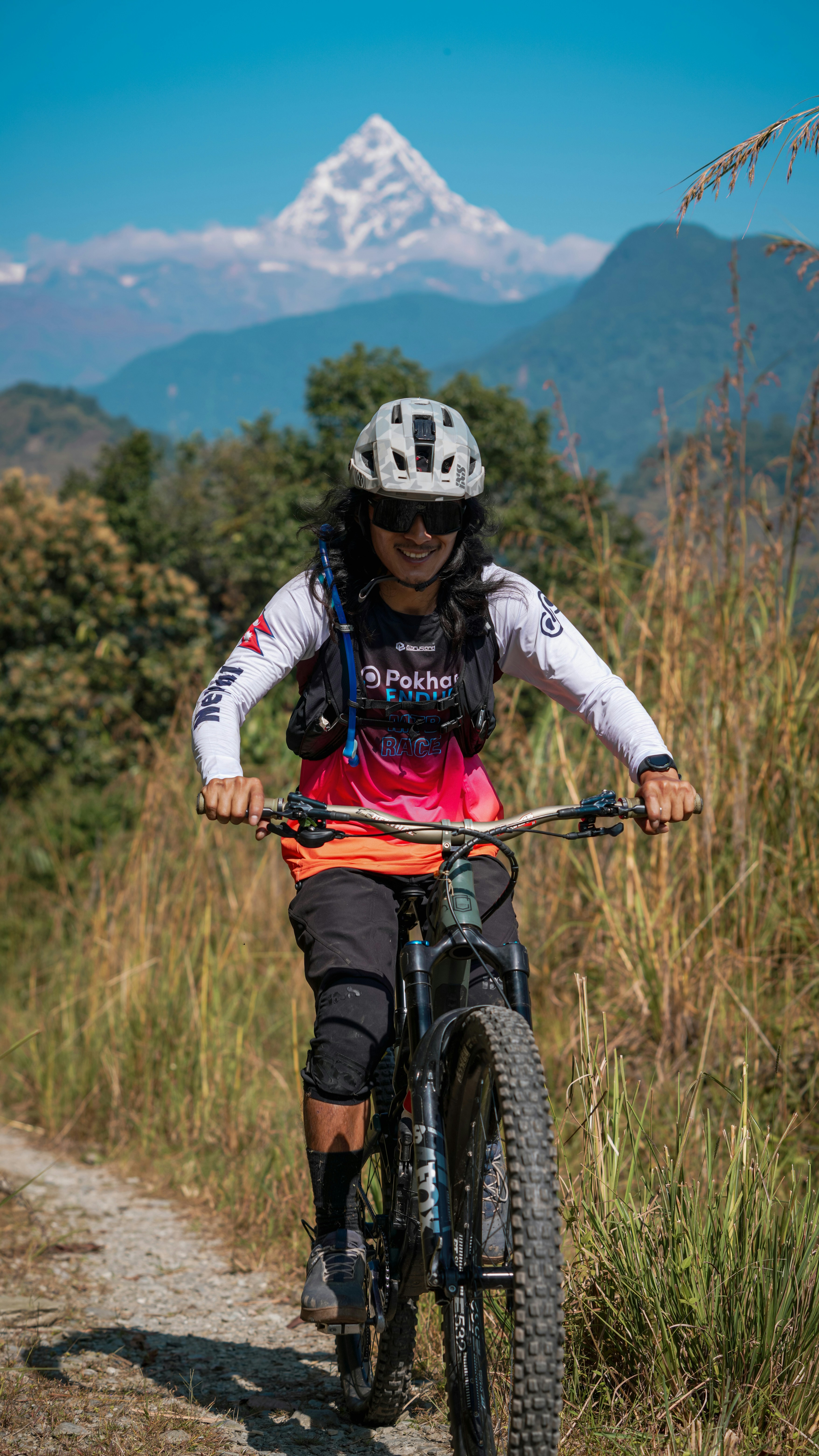 Woman mountain biking with snowy peak in background.