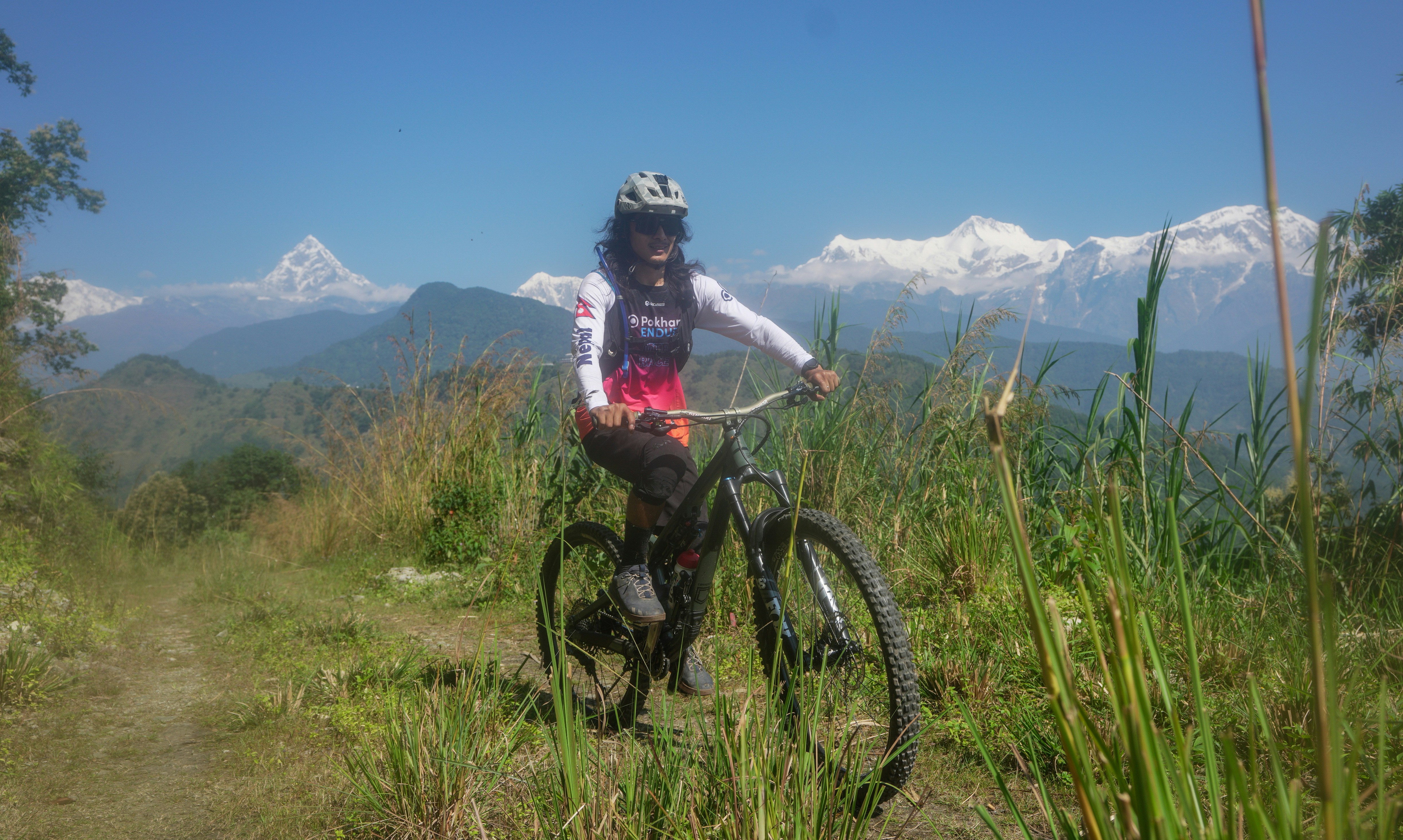 Woman mountain biking with snowy peaks behind