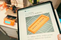 Tablet displaying 3D print progress with printer in background.