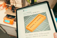 Tablet displaying 3D print progress with printer in background