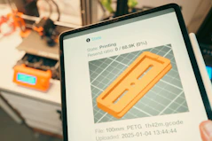 Tablet displaying 3D print progress with printer in background.