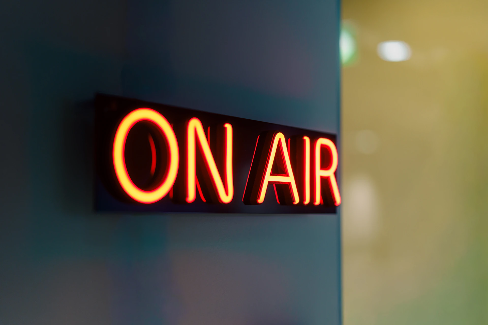 Red neon "on air" sign glowing on wall.