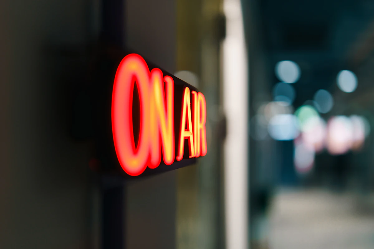 Red neon on air sign glowing in a dark radio broadcast studio