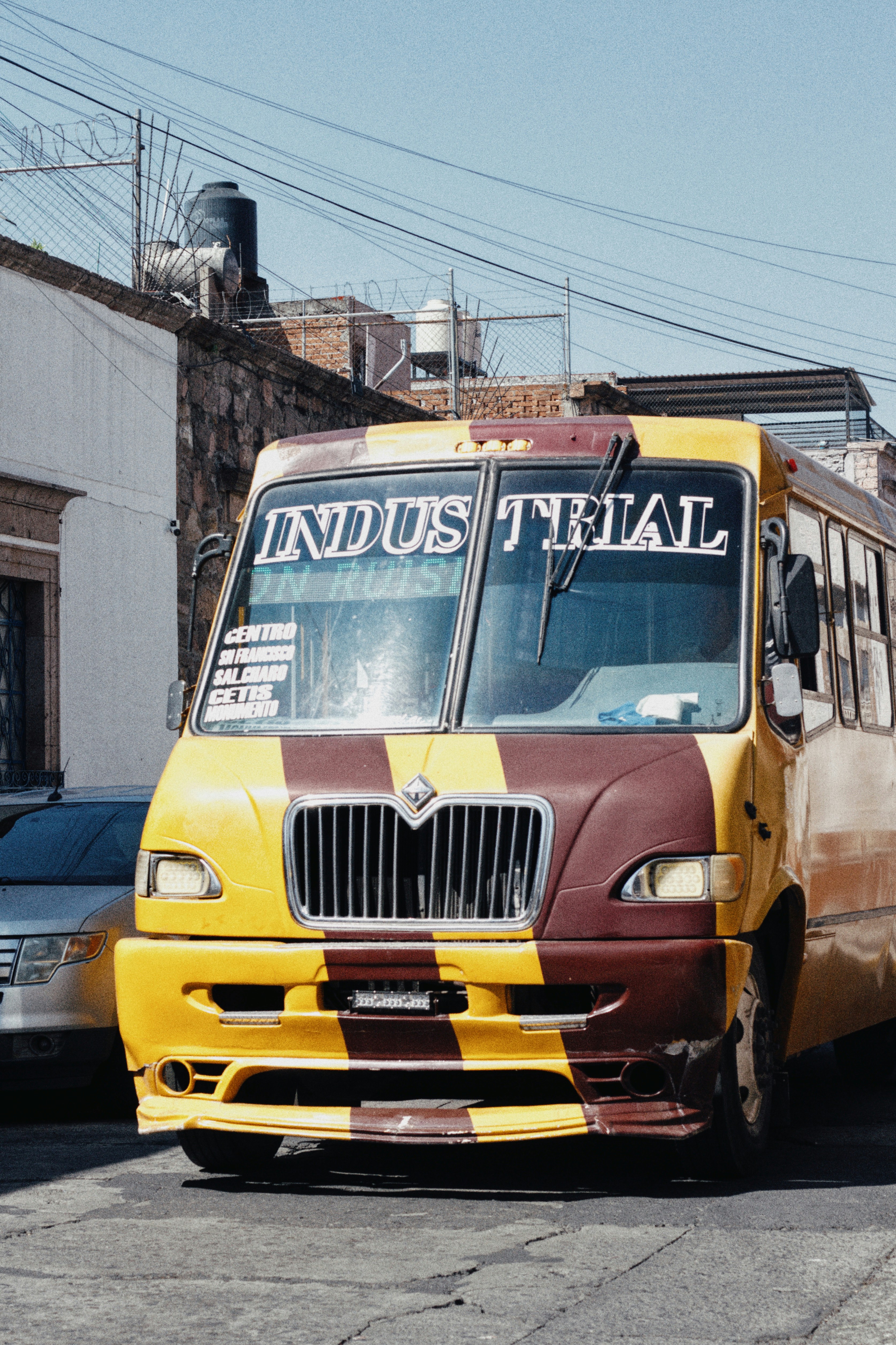Yellow and maroon bus with "industrial" sign on windshield.