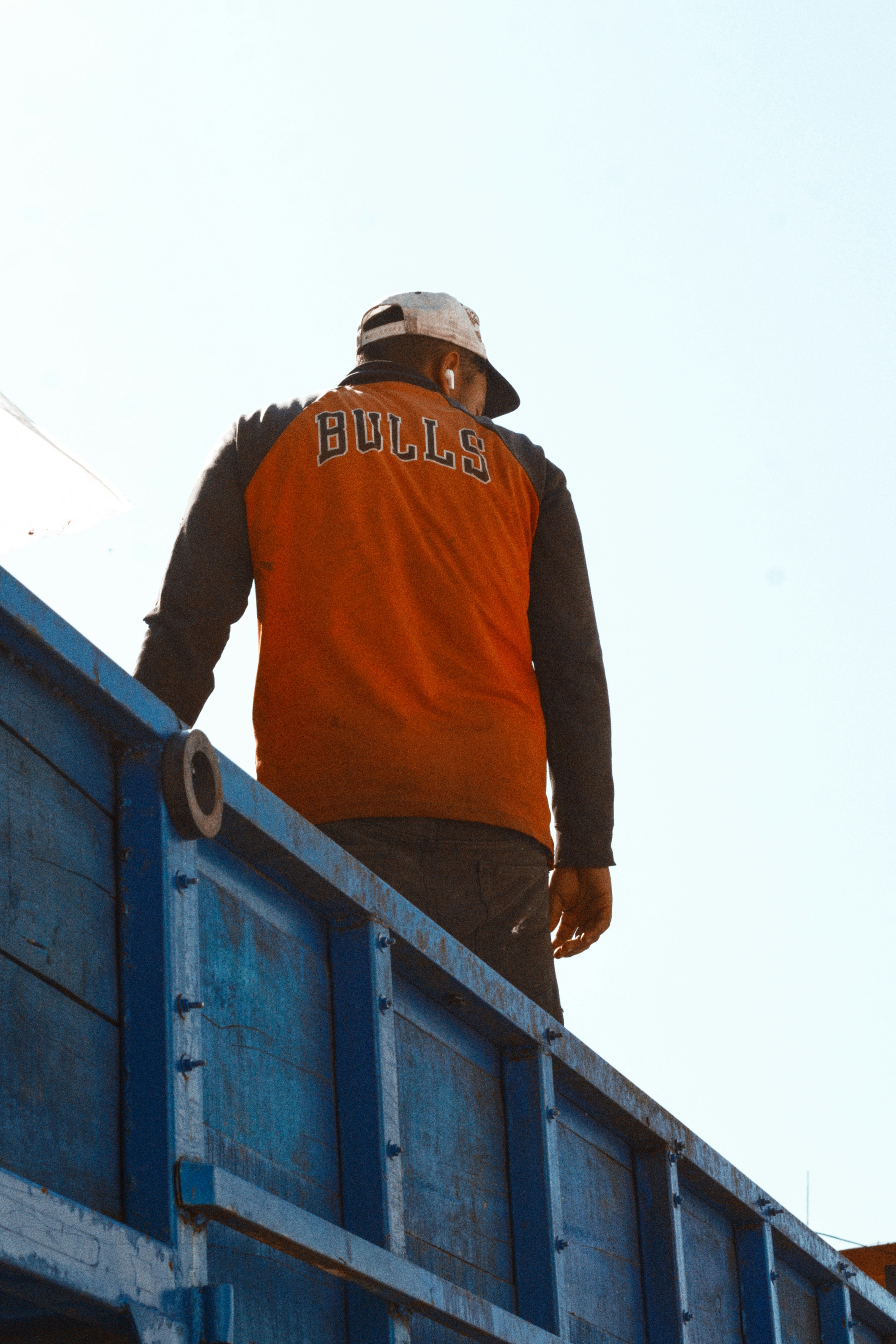 Man in bulls shirt on top of blue truck