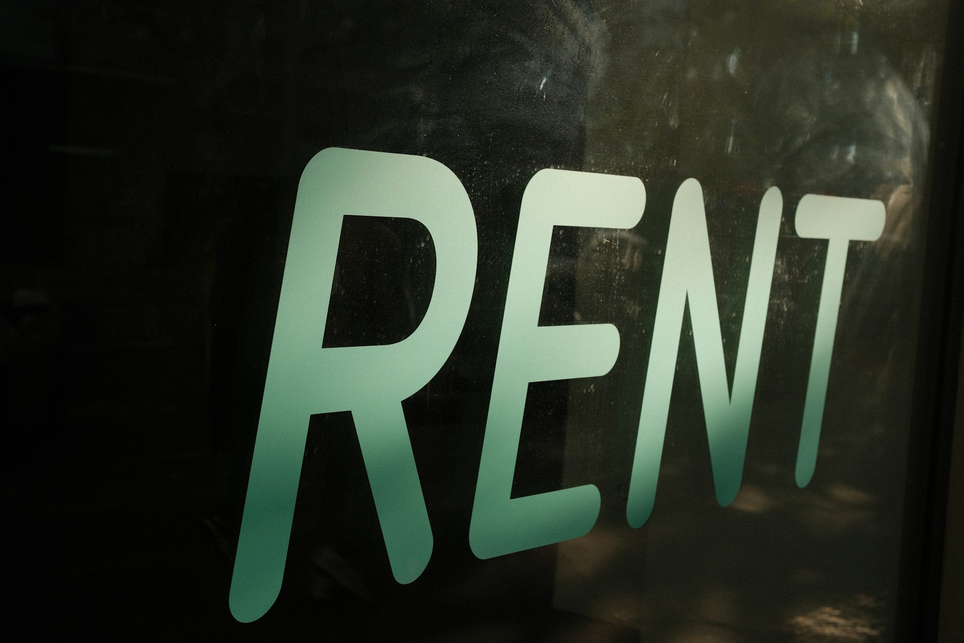 The word rent is written on a dark surface.