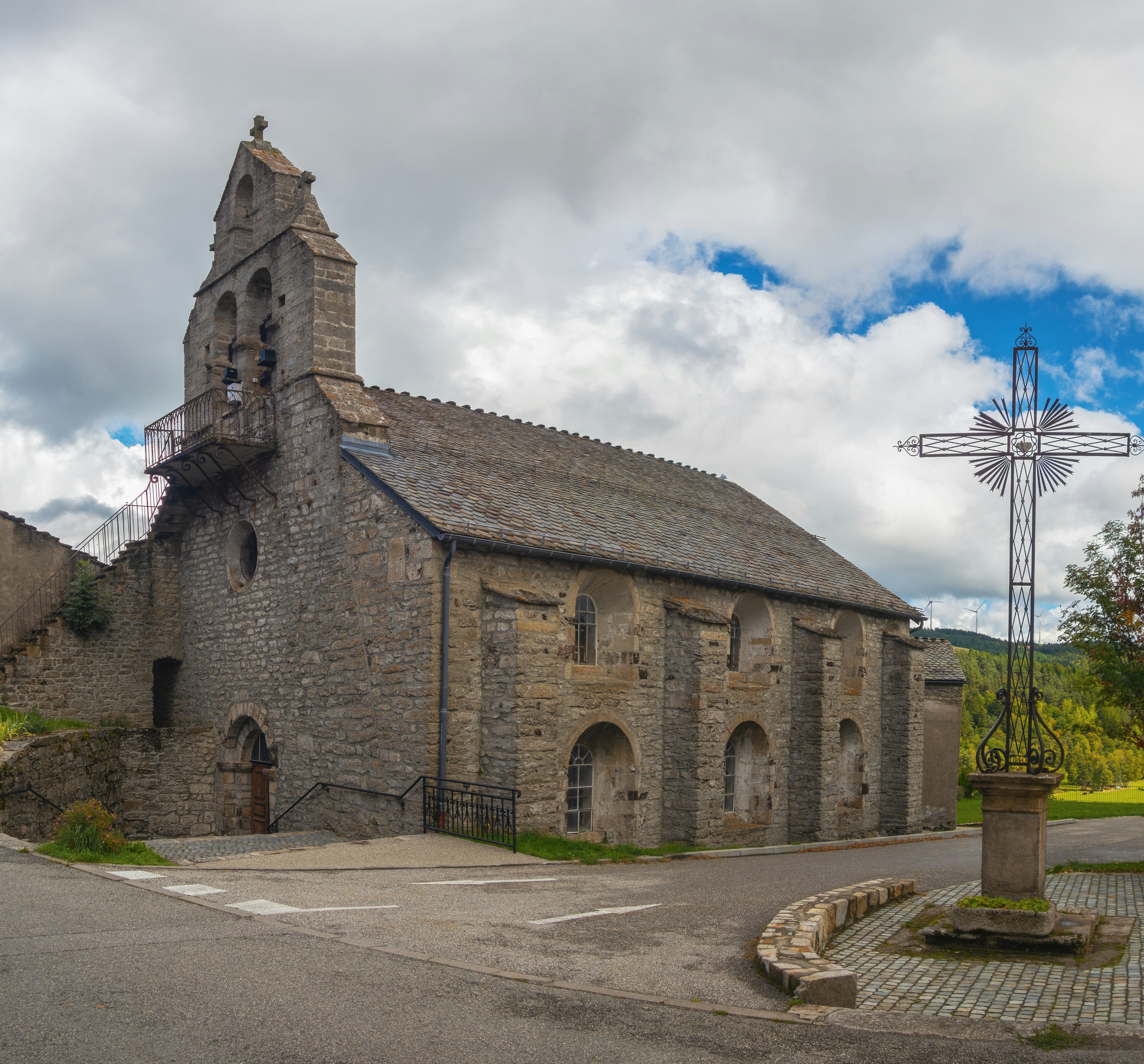 Stone church with a bell tower and a large cross.