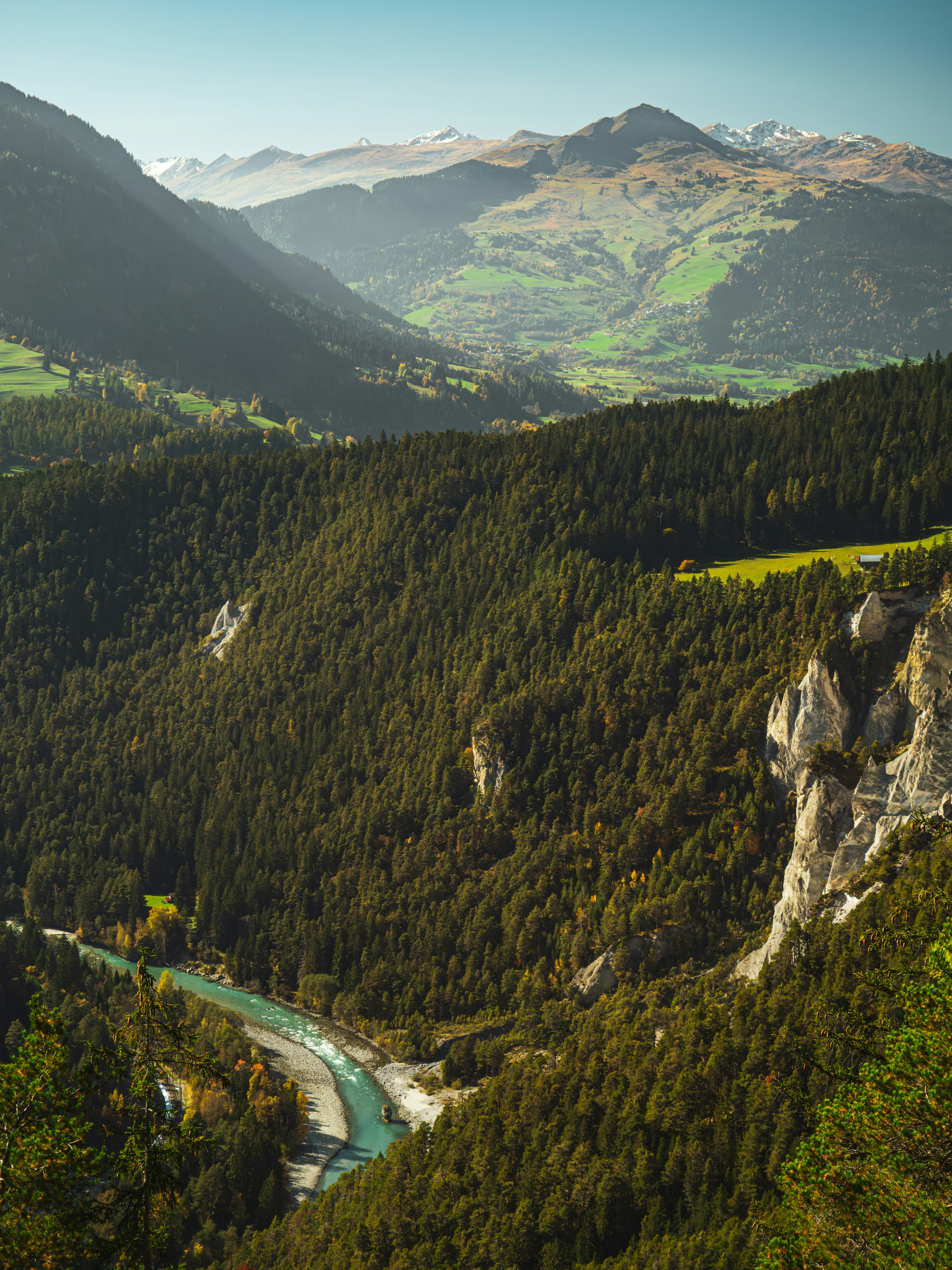 Turquoise river flows through a lush green mountain valley.