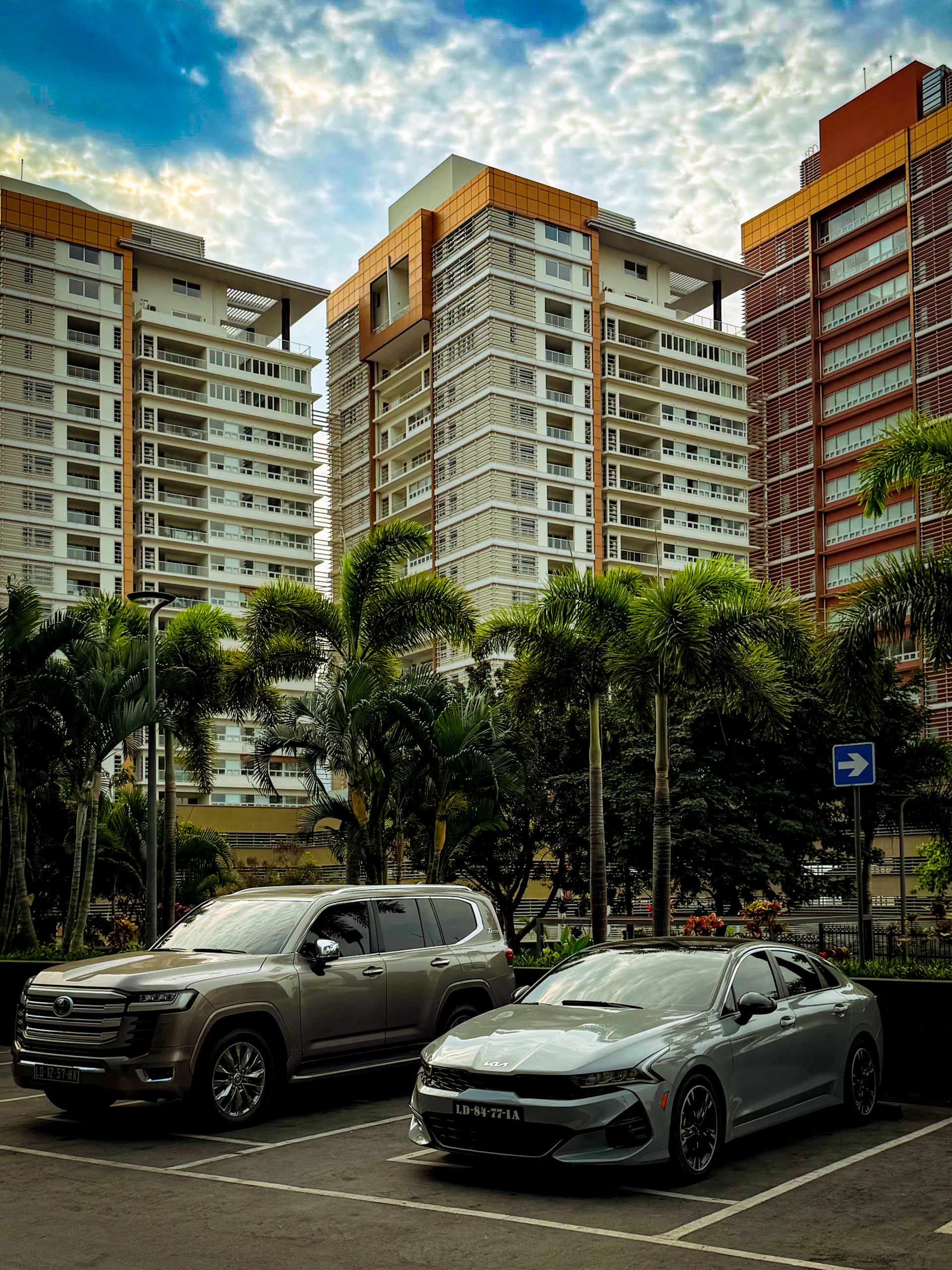 Two cars parked in front of modern buildings
