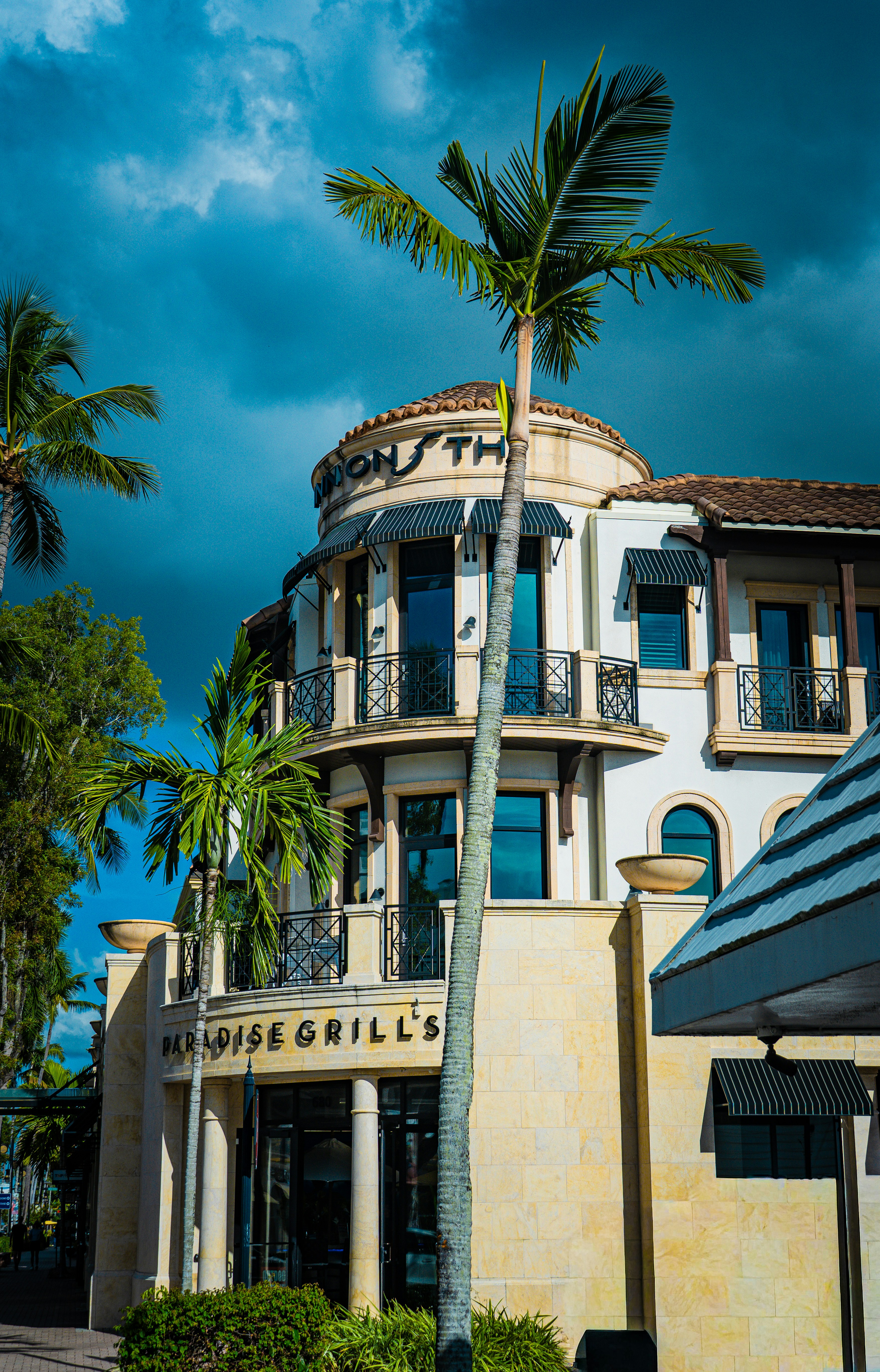 A building with palm trees and dramatic sky.