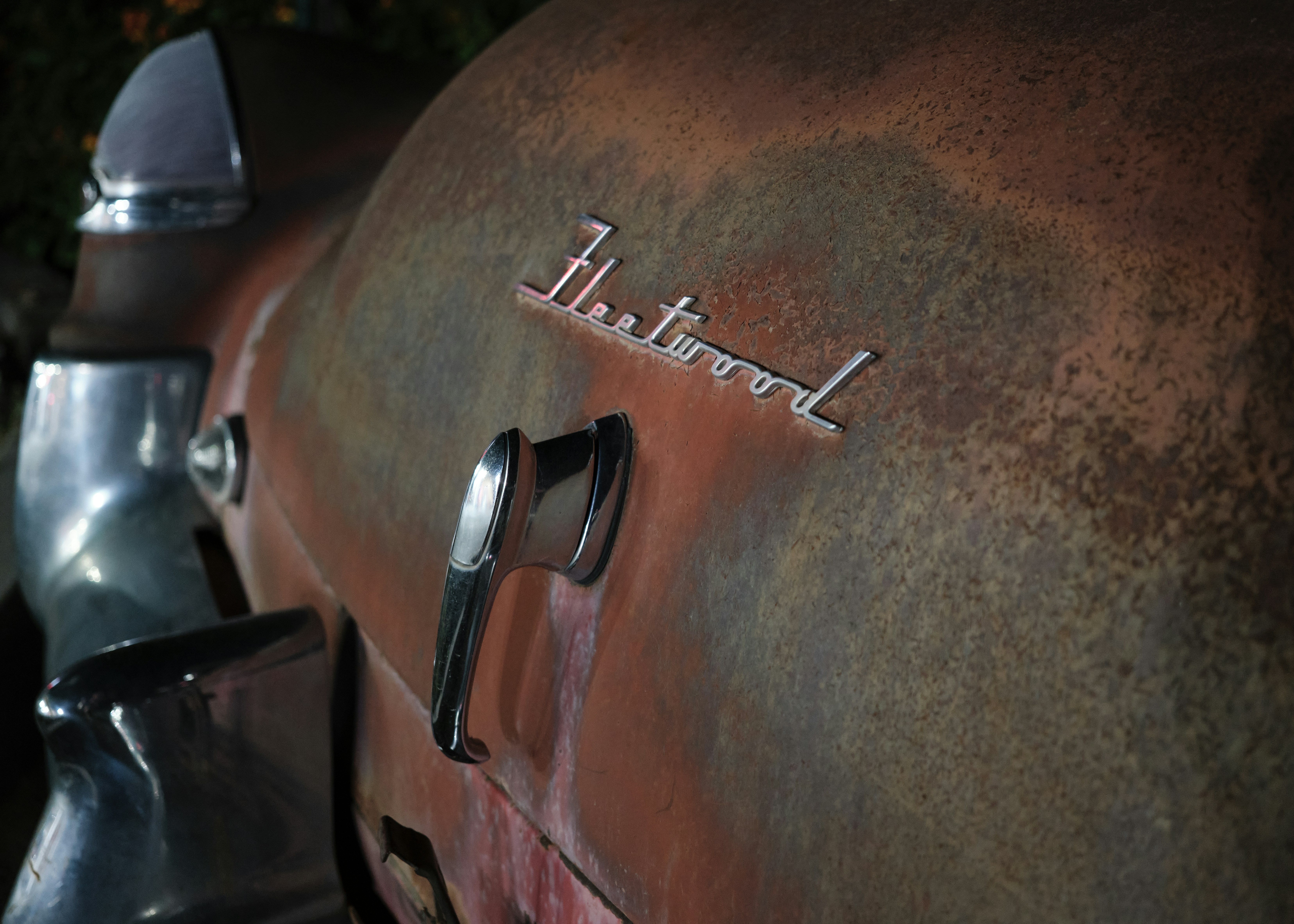 Close-up of rusted car emblem with chrome details.