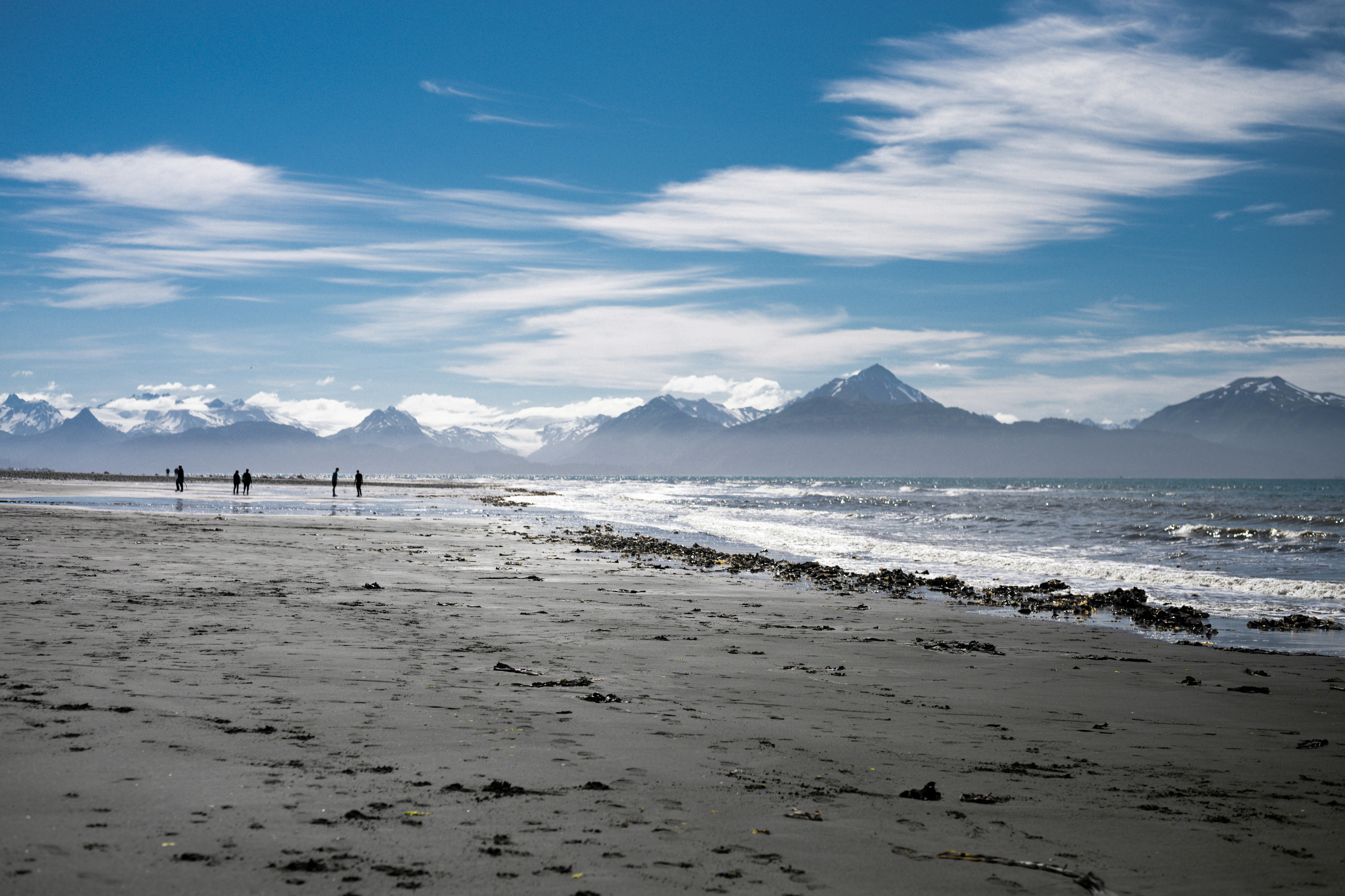 Sandy beach with distant mountains under a cloudy sky.
