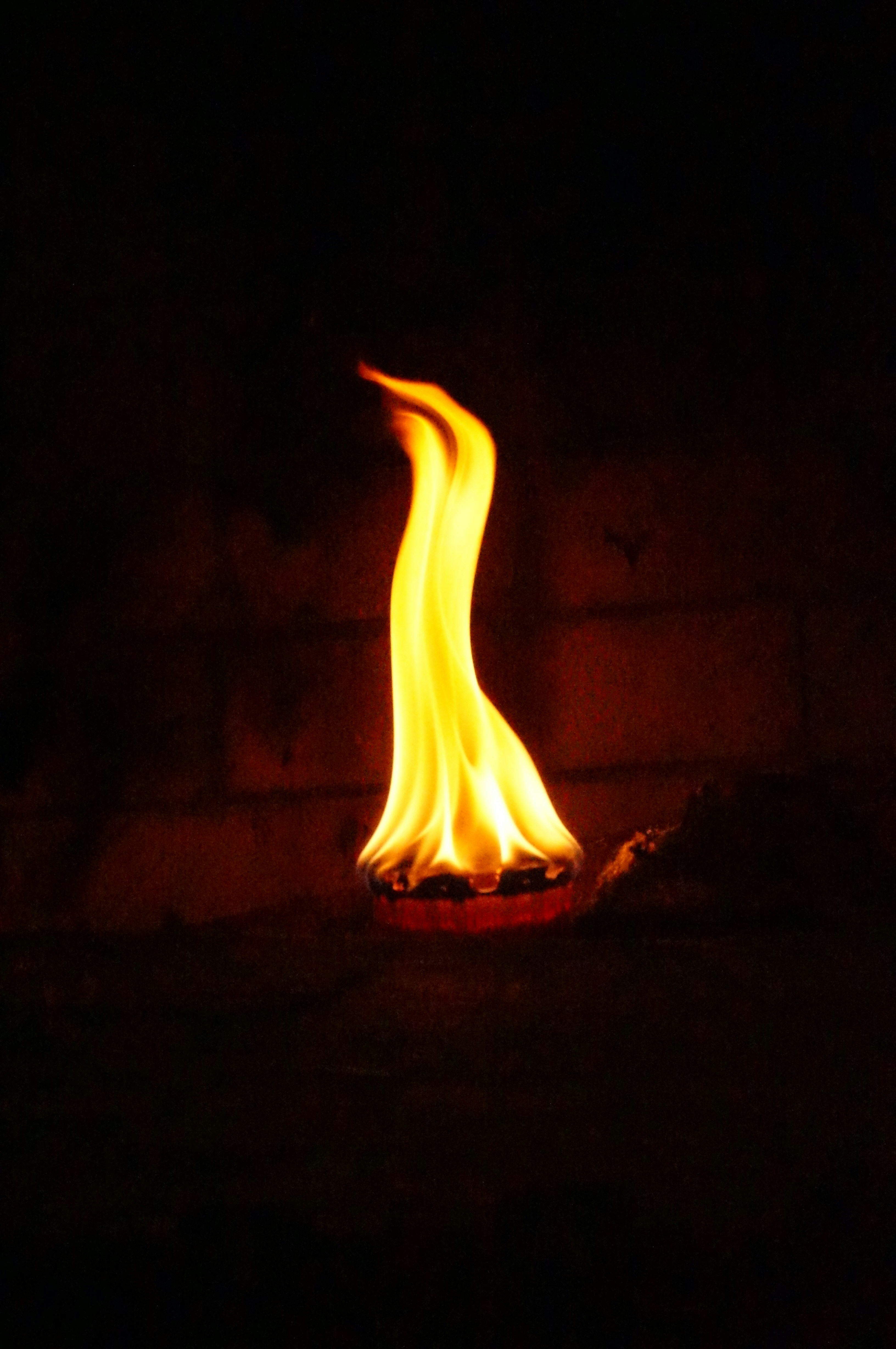 A single flame burns brightly in darkness