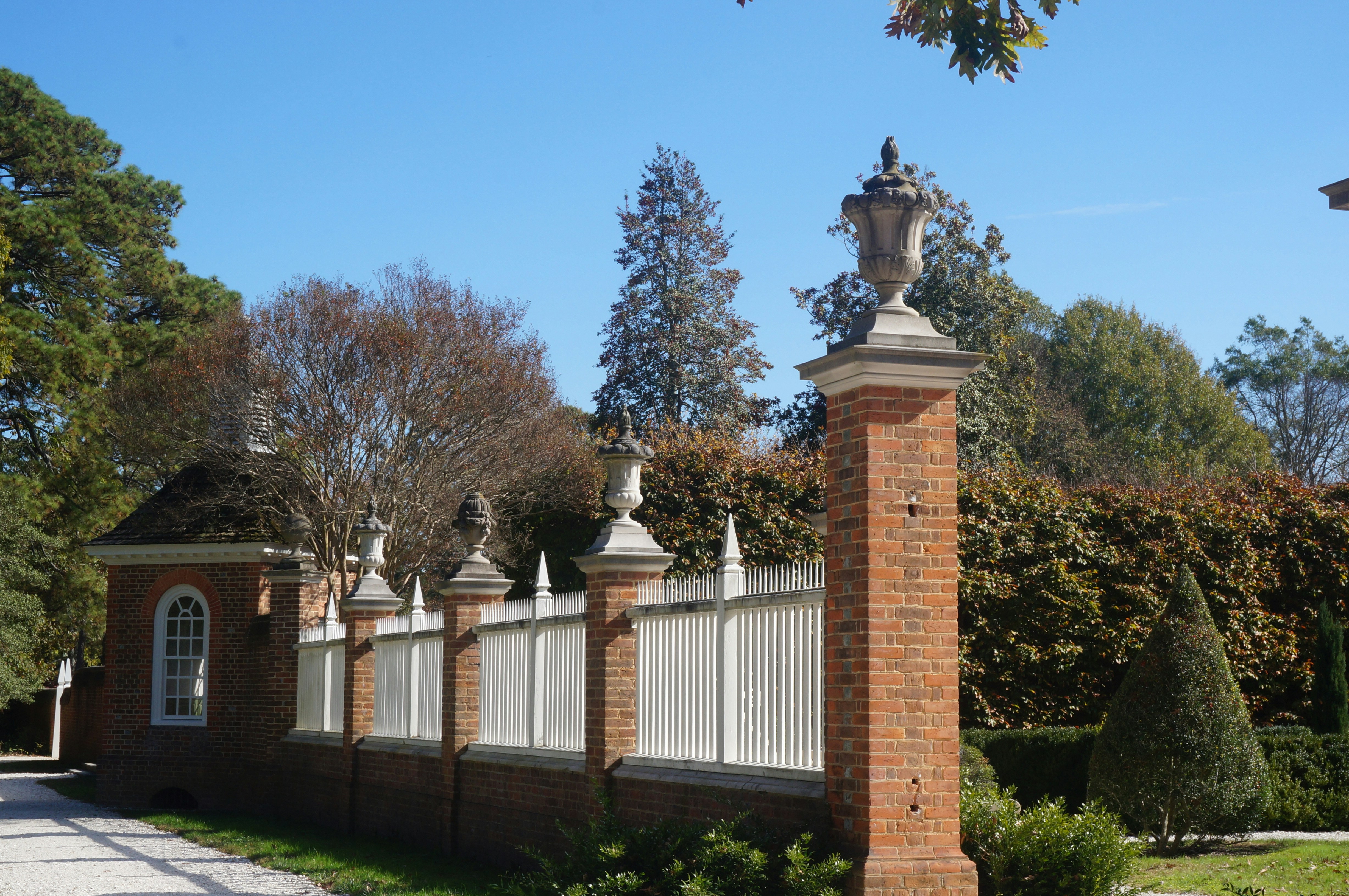 Brick pillars and white fence with ornate tops