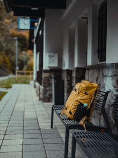 Yellow backpack on a bench at a train station.