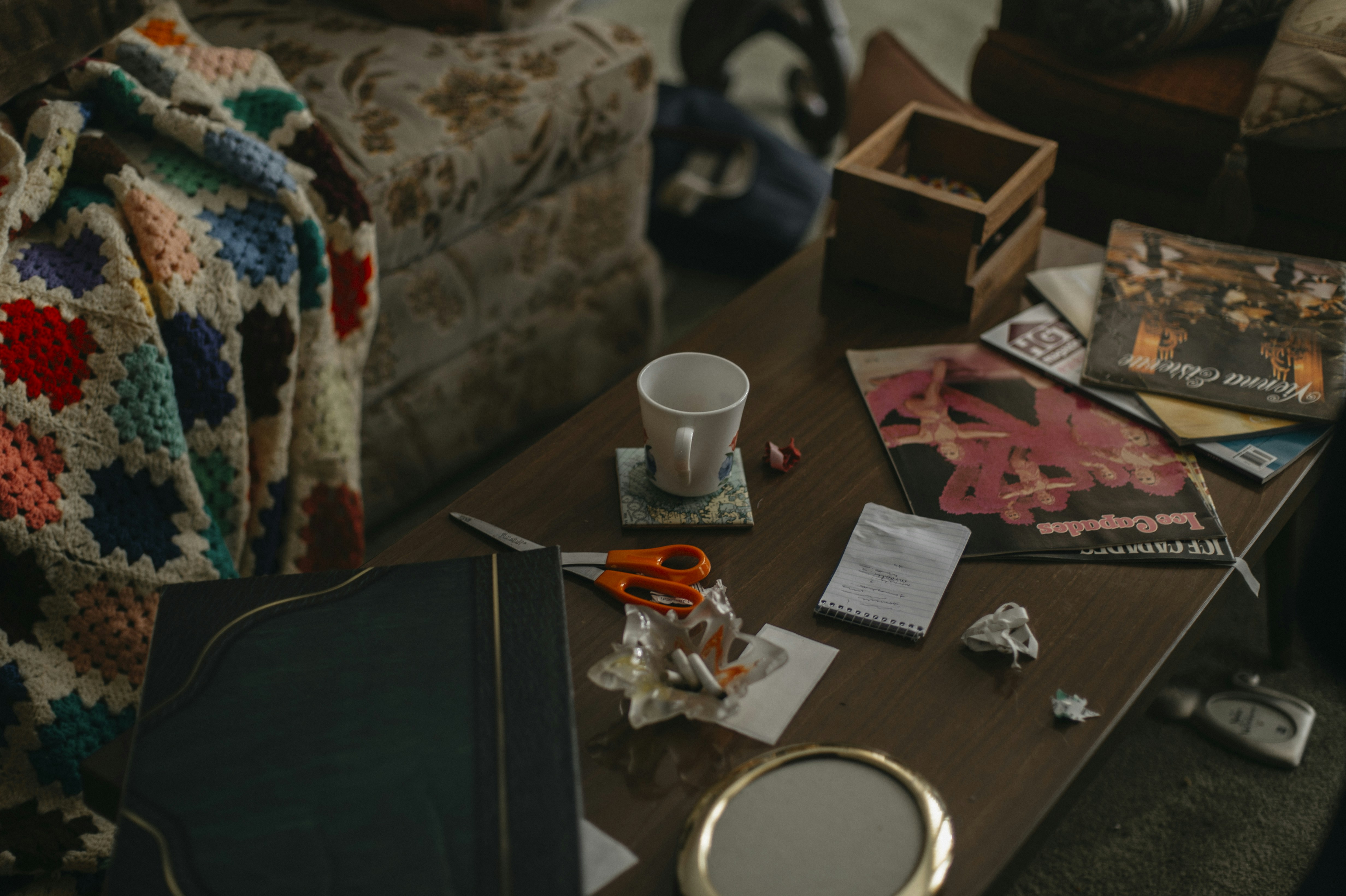 Crocheted blanket draped over a couch with items on table.