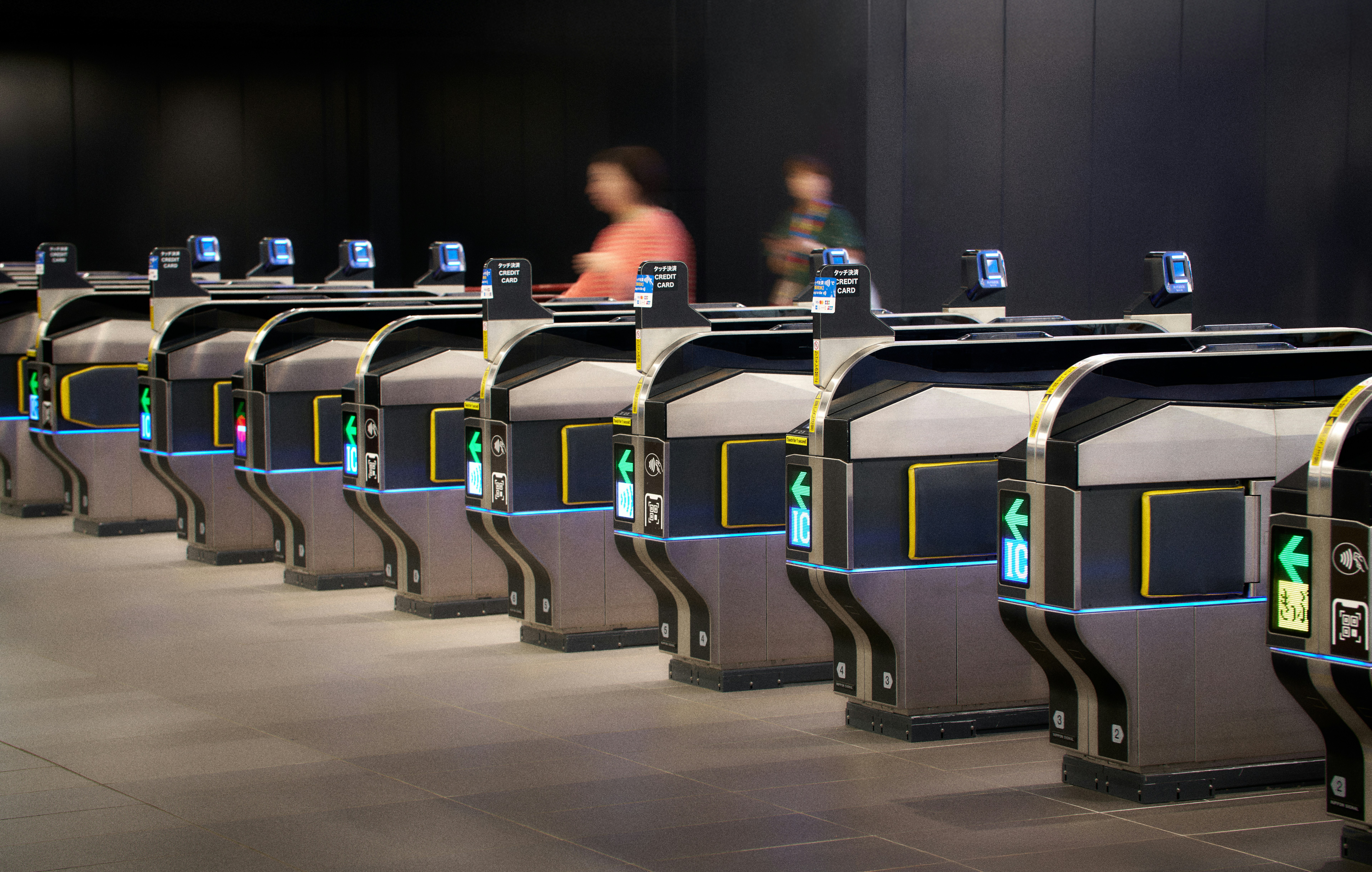 People passing through modern ticket gates in a station.
