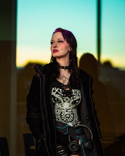 A woman with purple hair and alternative clothing looks away.