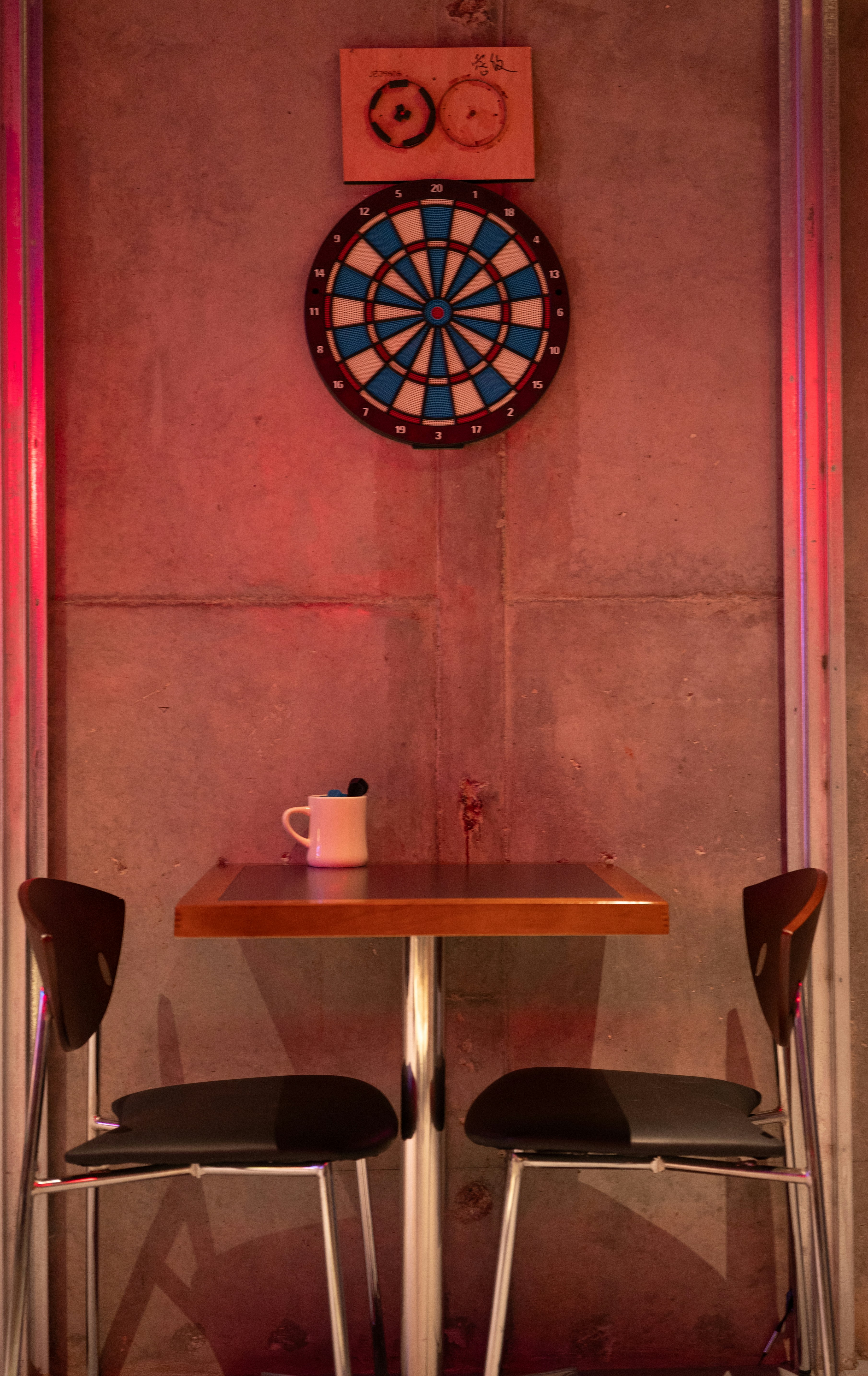 Dartboard above a table with two chairs