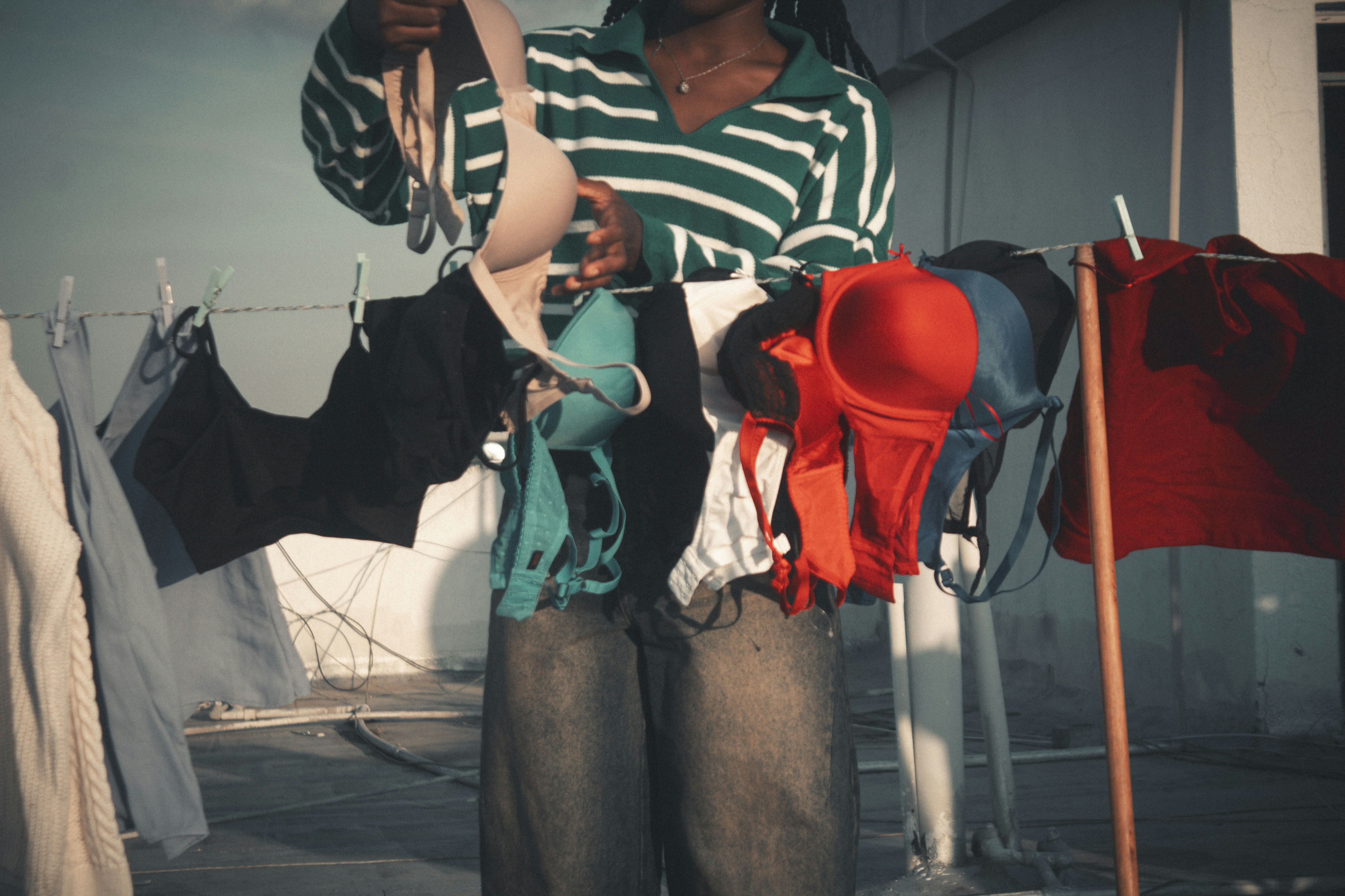 Person holding bras and clothes on clothesline