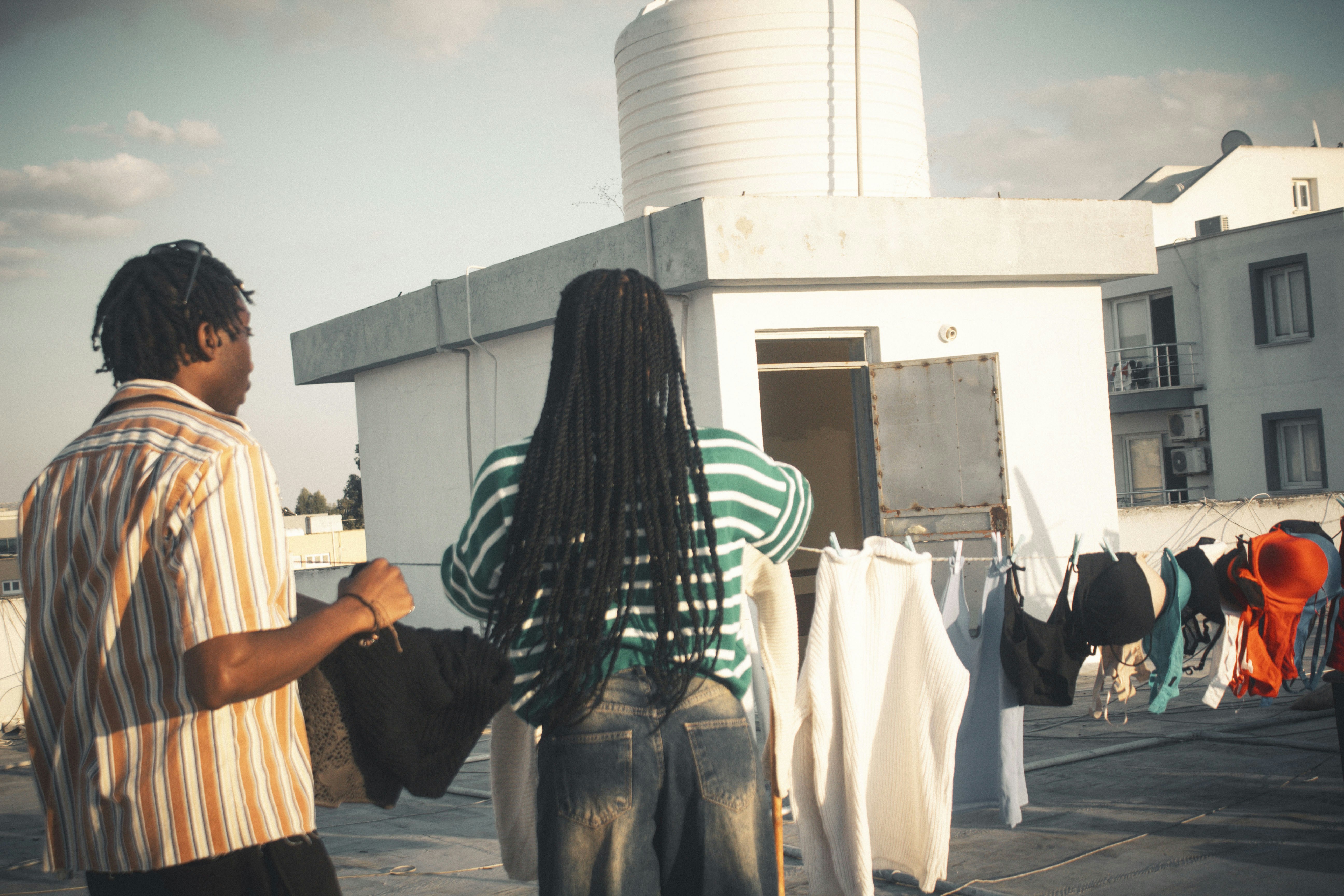 Two people hanging laundry on a rooftop
