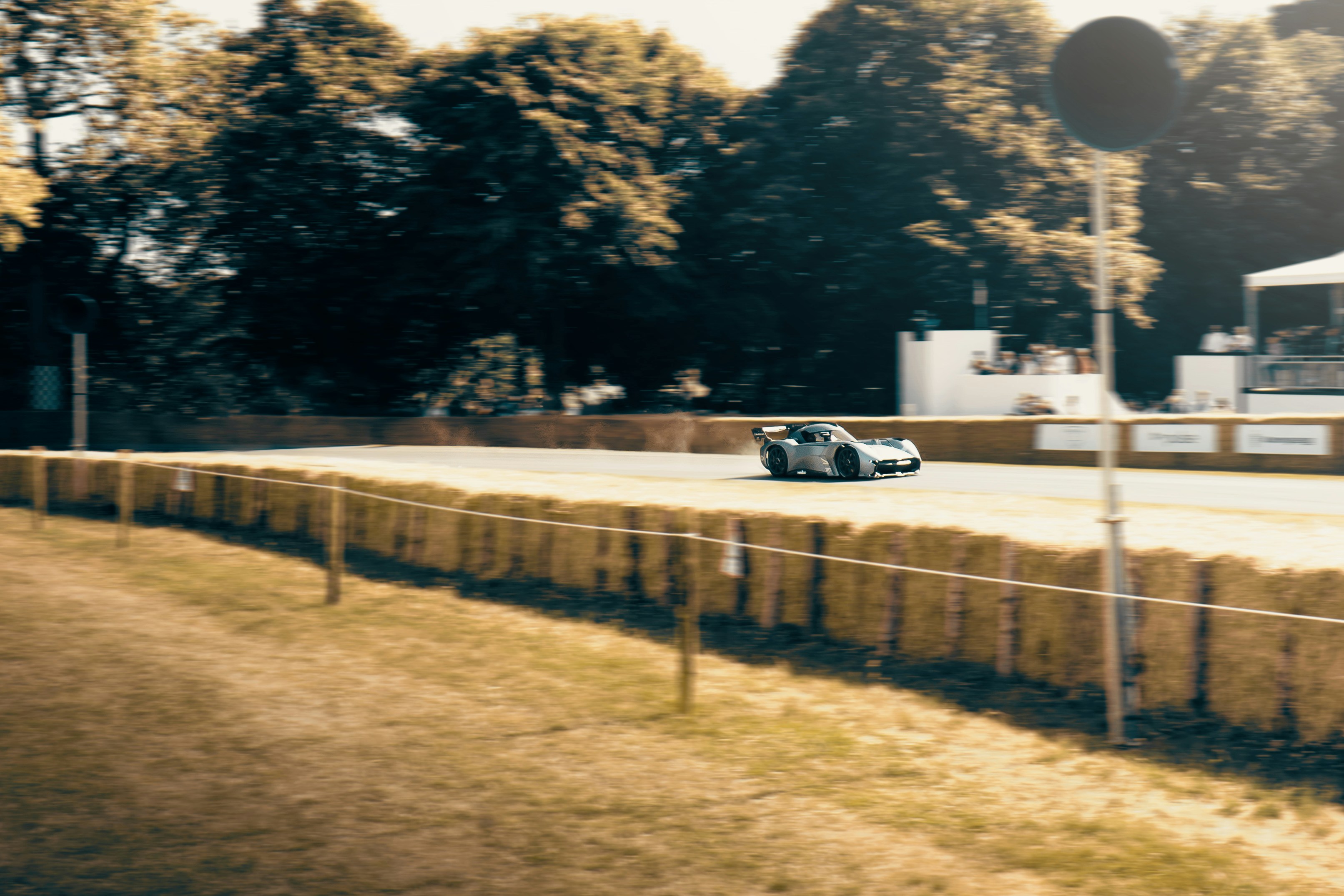 A race car speeds down a track with hay bales.