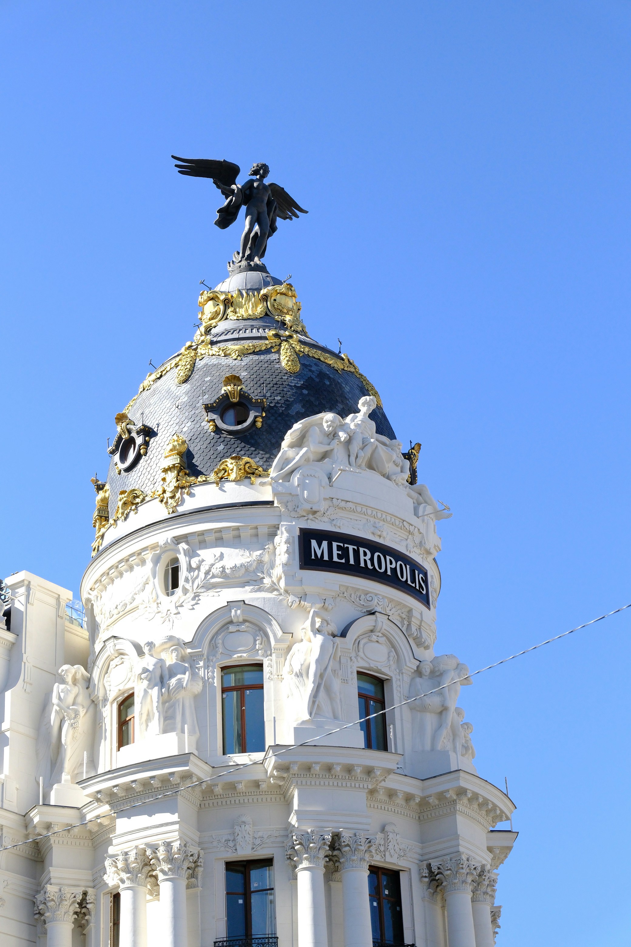 Metropolis building with statue against blue sky