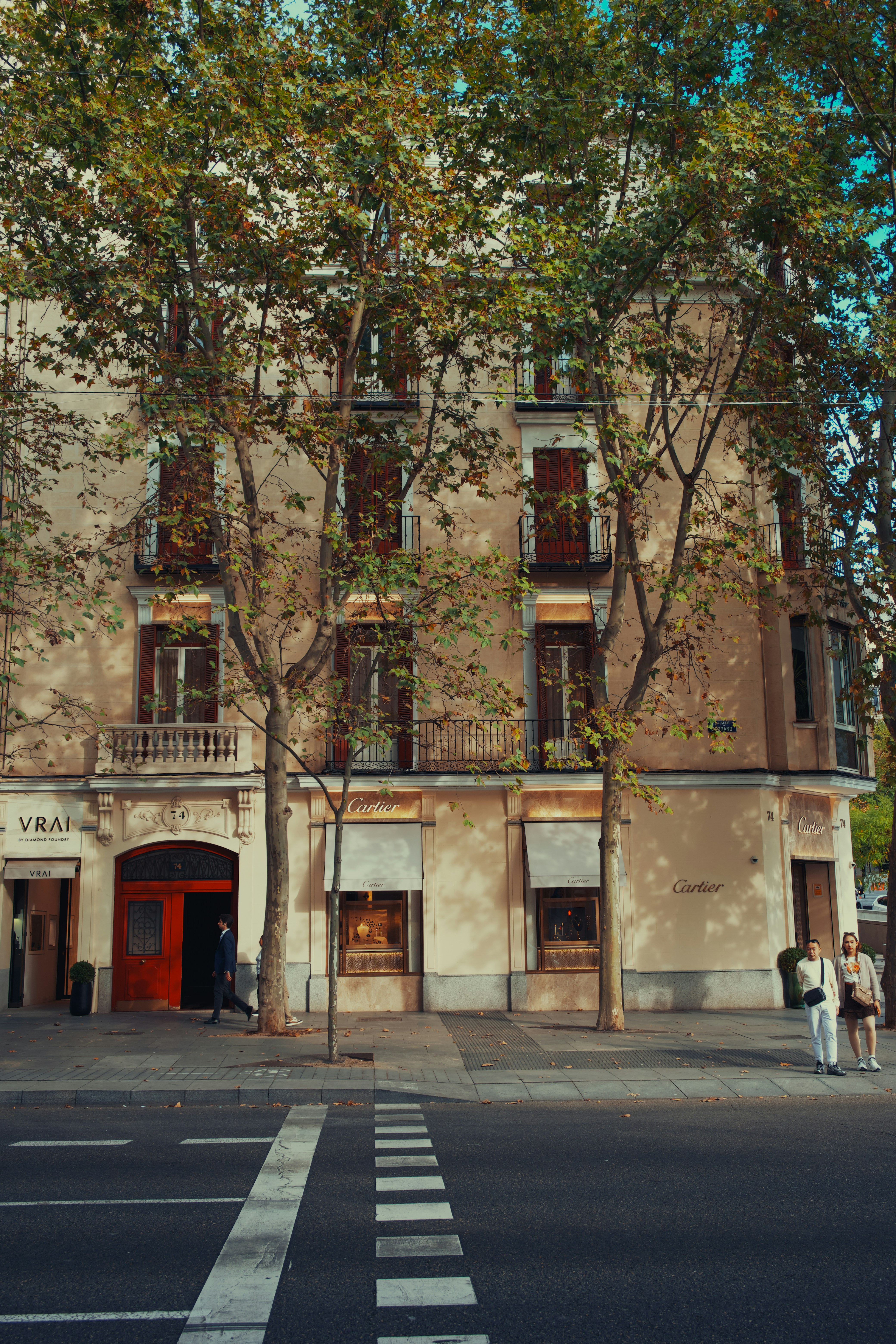 Building with trees and people on sidewalk.