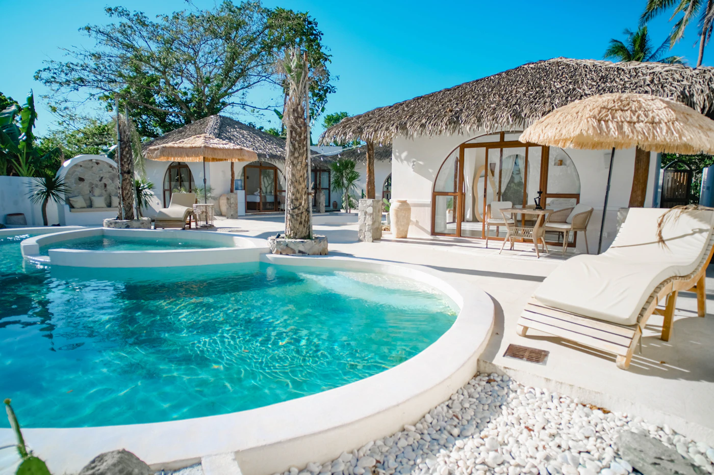 A resort pool beside thatched roof bungalows