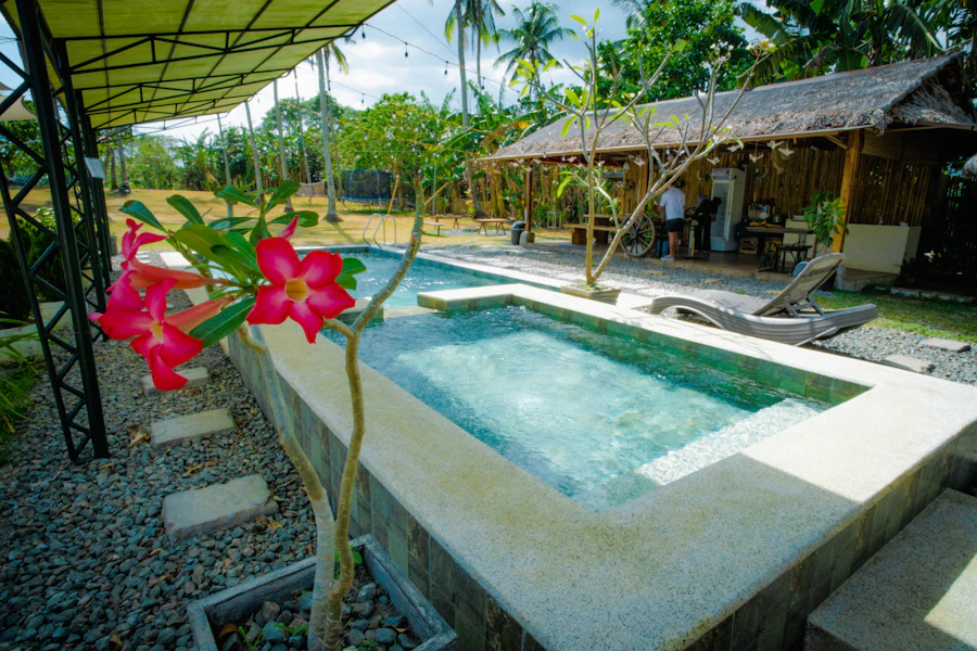 The garden corner of the pool with tropical flowers and the bamboo hut