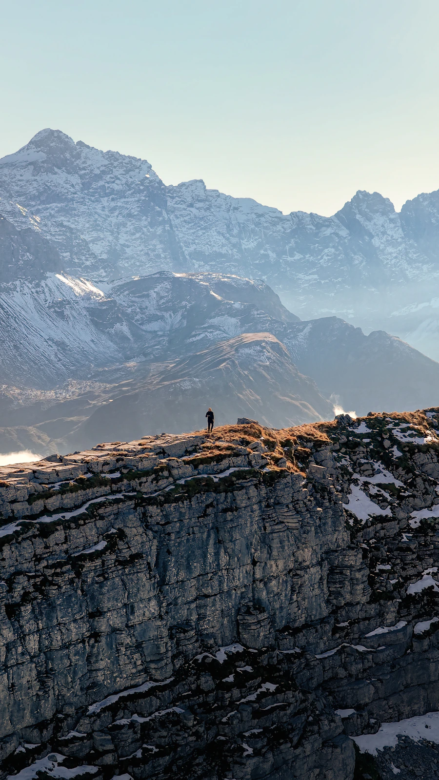 Lone explorer standing on a mountain ridge at sunset