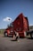 Man crouching in front of a red semi-truck.