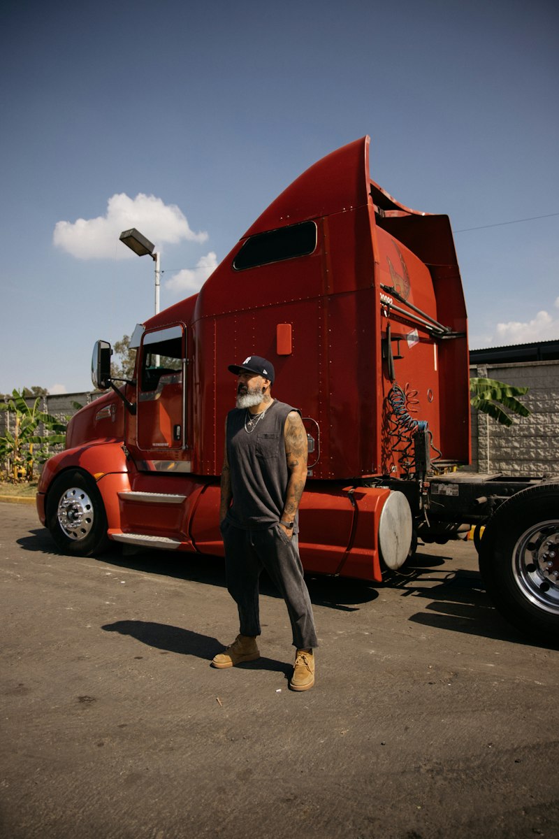 Homem usando boné trucker ao lado de caminhão