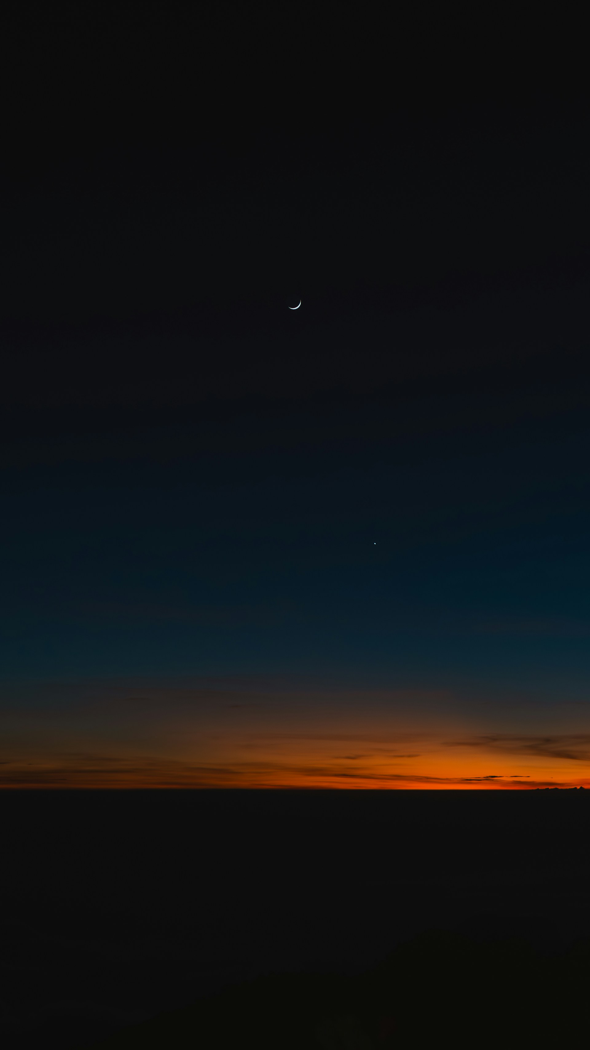 Crescent moon and star over horizon at sunset horizon