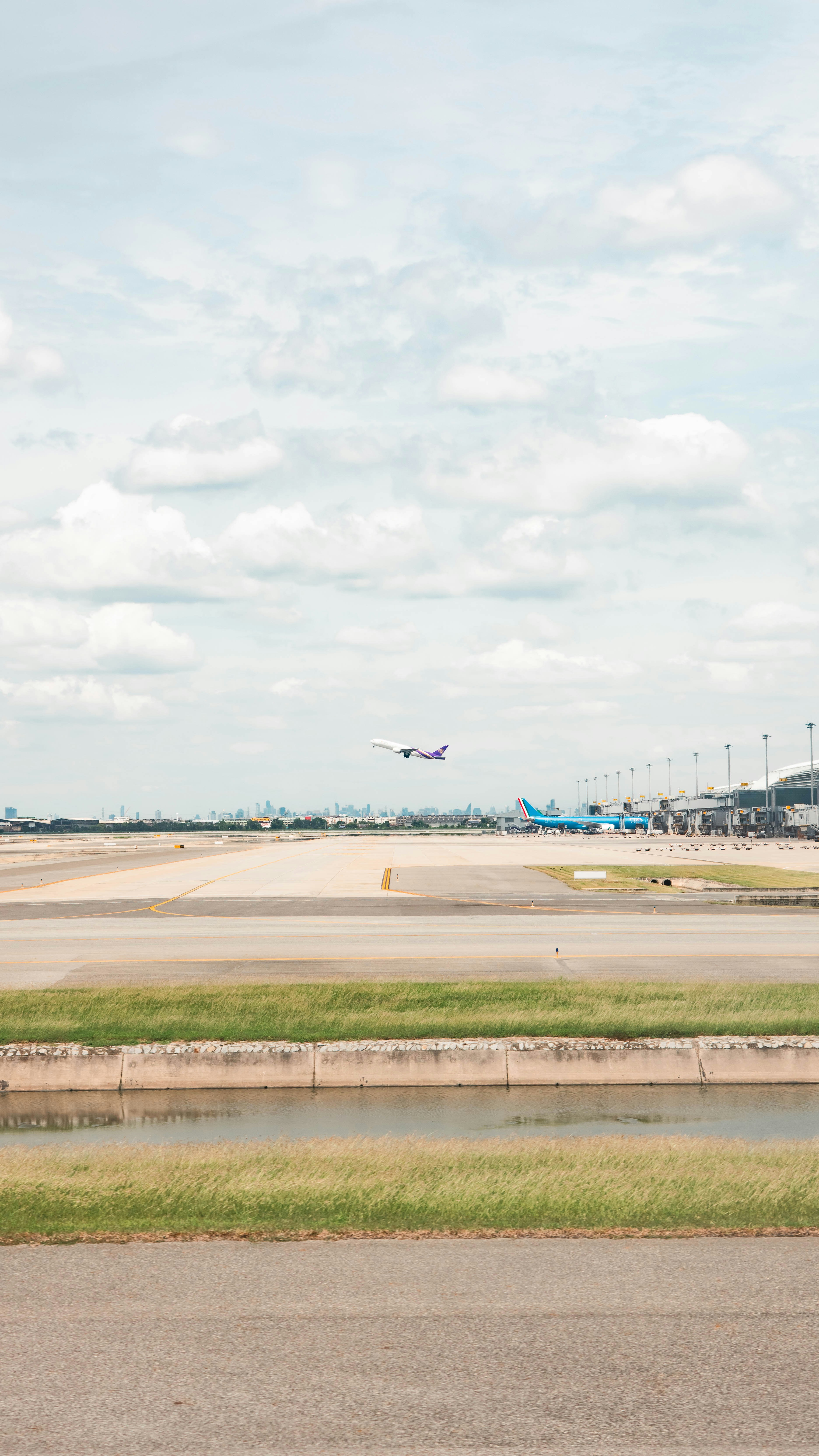 Airplane taking off from airport runway with buildings in distance