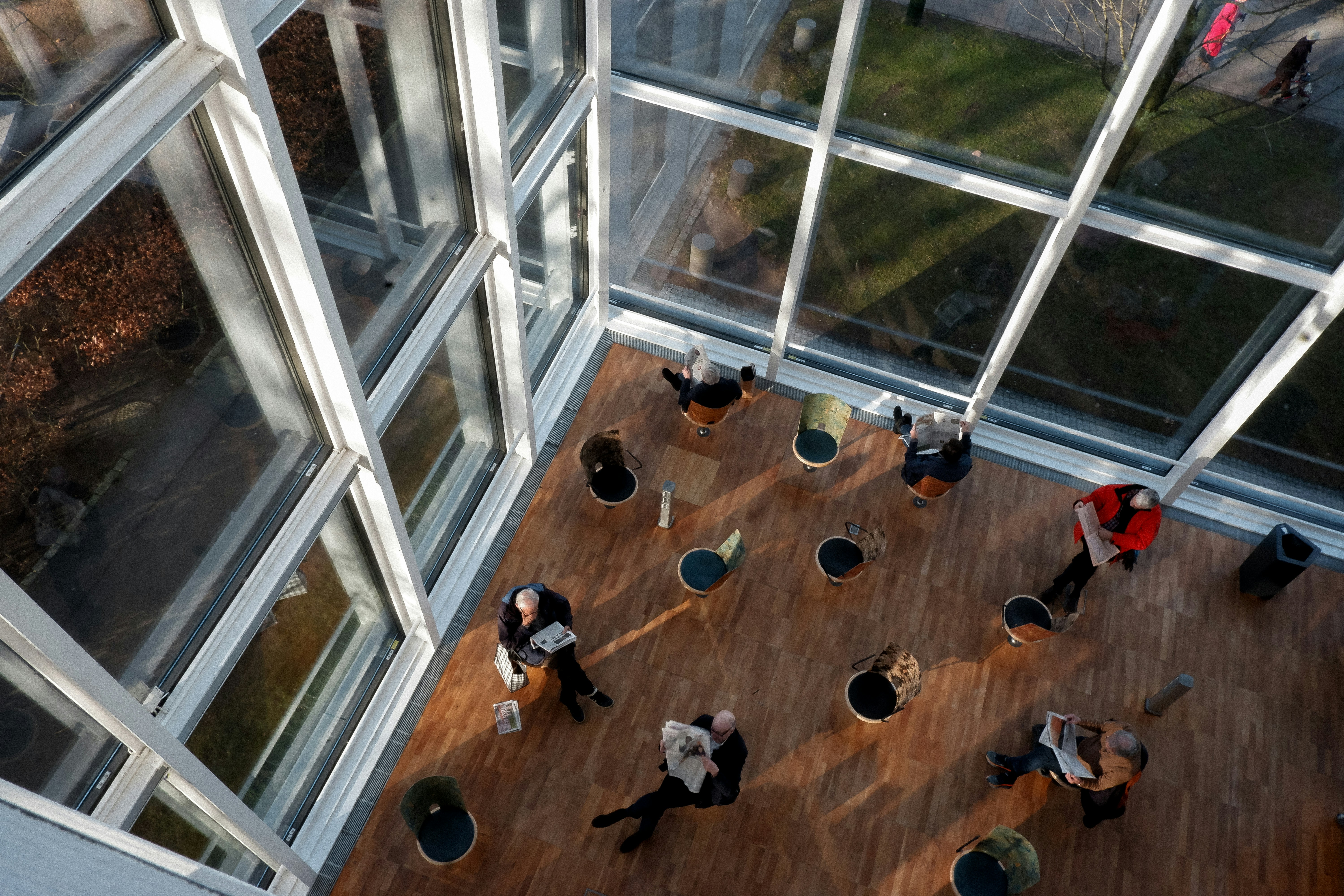 People sitting and reading in a sunlit atrium lobby.