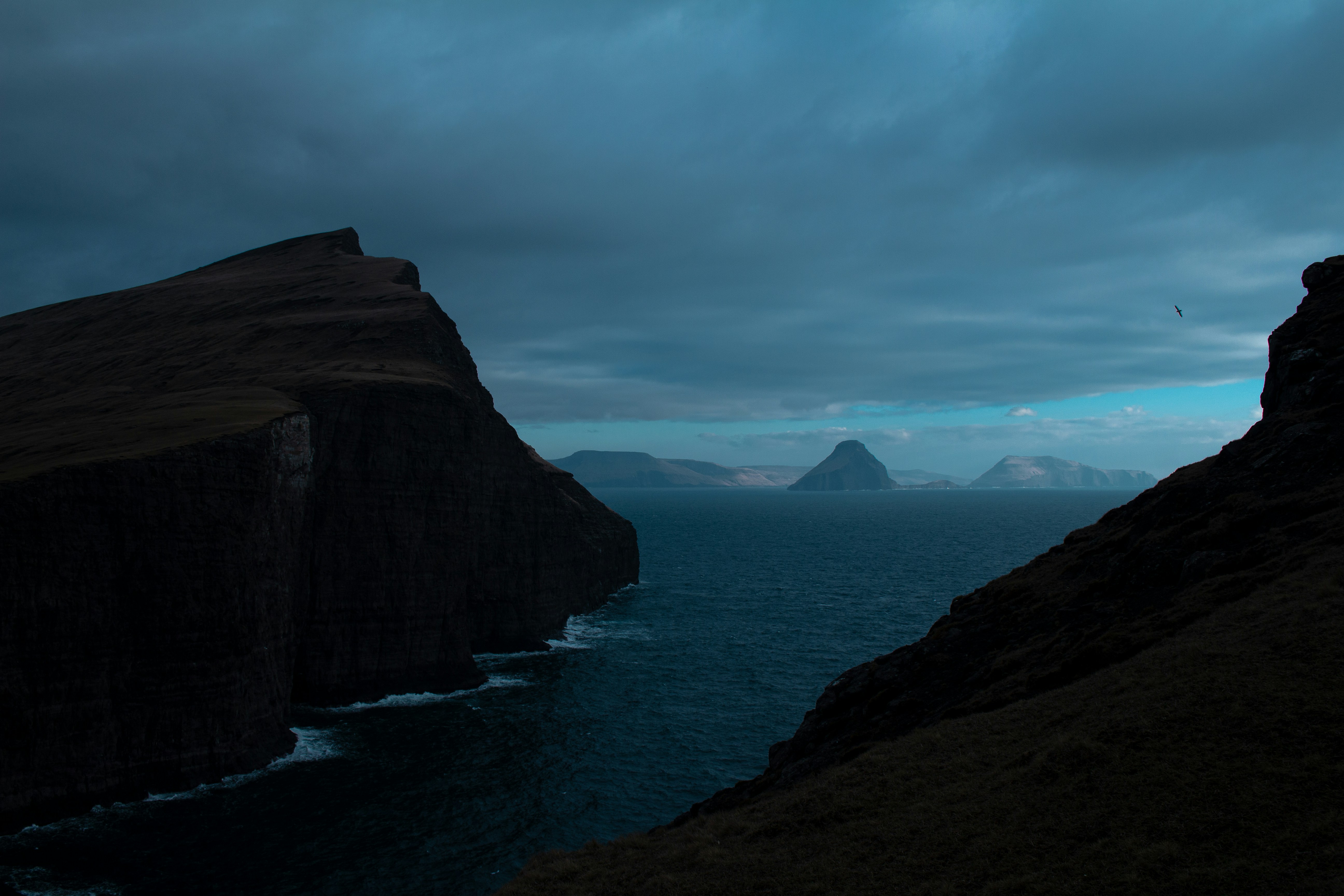 Dramatic cliffs overlook a dark, choppy sea under moody skies.