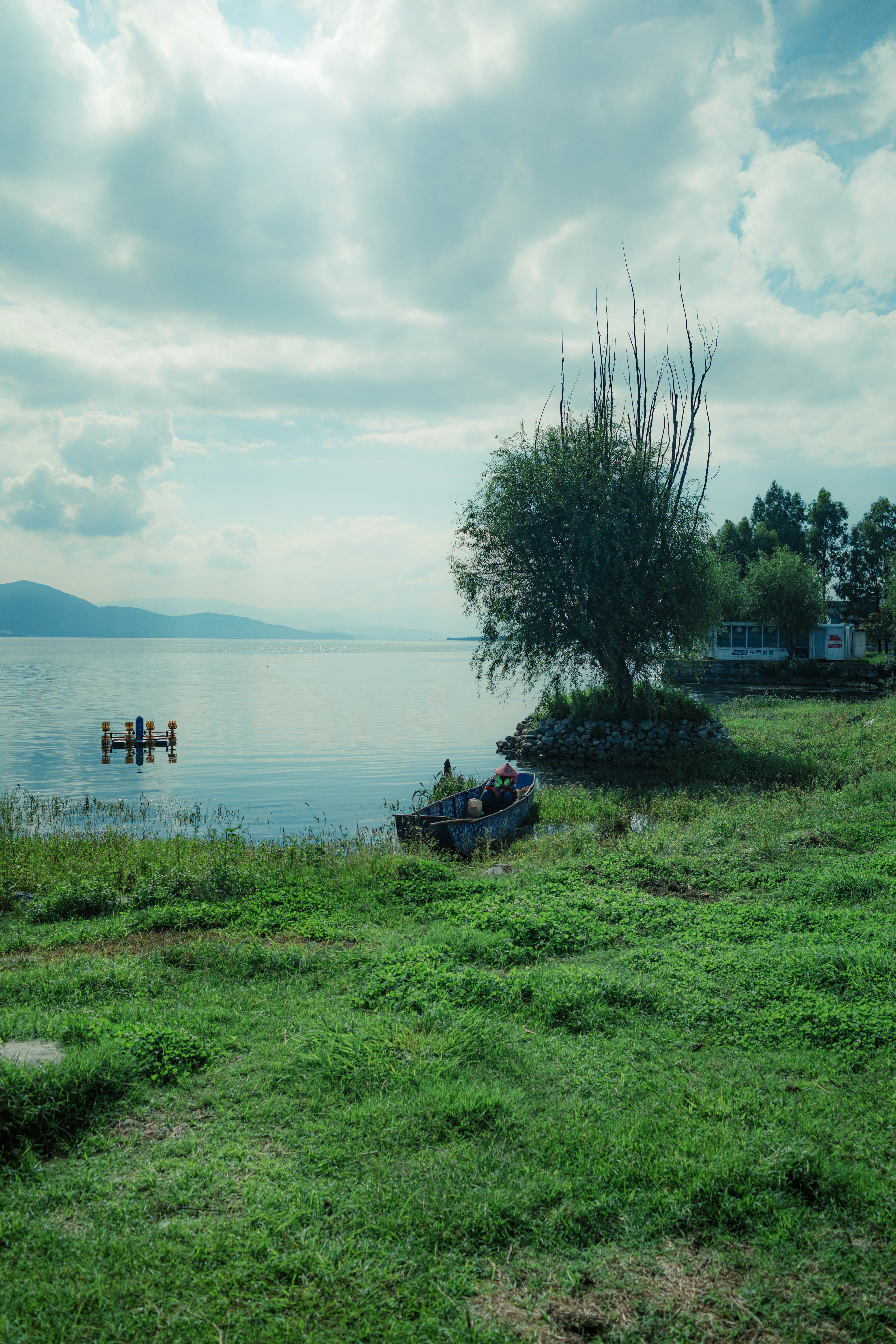 Lac calme avec un petit bateau et de l’herbe verte
