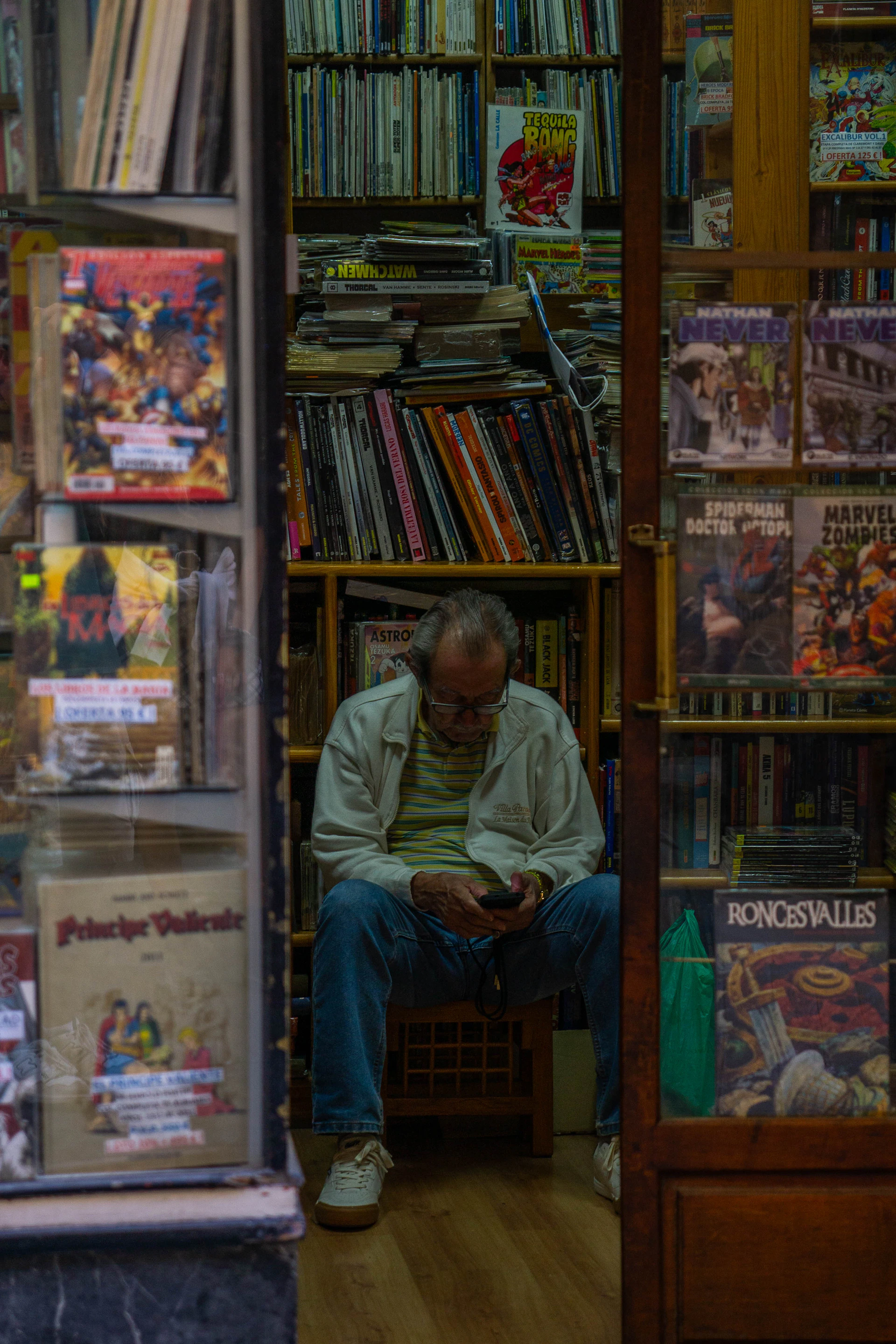 Man sitting in a comic book store looking at phone