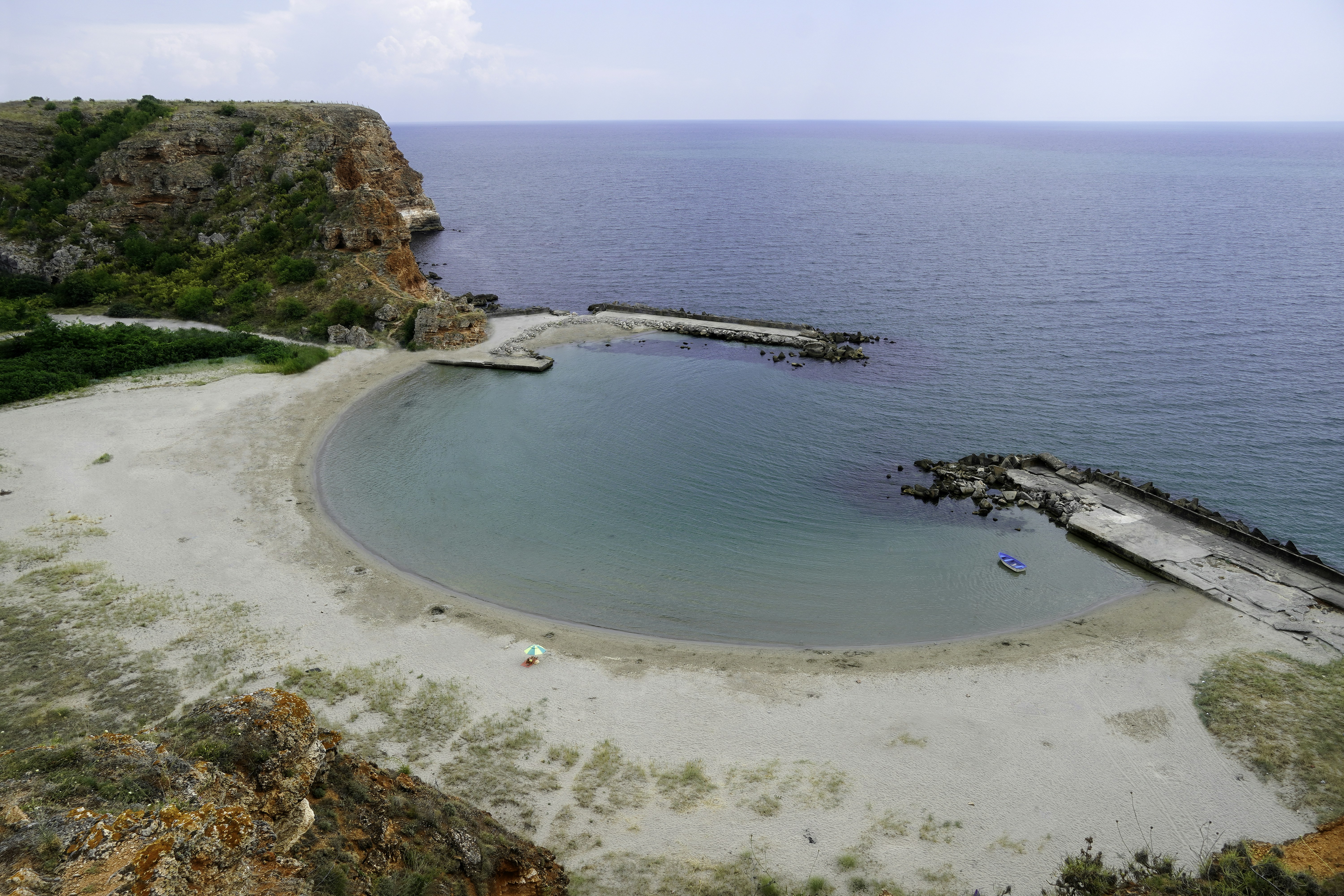 A secluded beach with calm turquoise water and rocky cliffs.