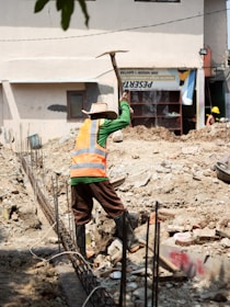 Construction worker digging with a pickaxe at a site.