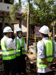 Three people in hard hats and vests talking.