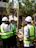 Three people in hard hats and vests talking.