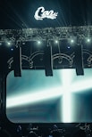 Stage lights illuminate a large screen with a cross