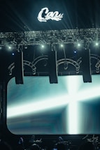 Stage lights illuminate a large screen with a cross