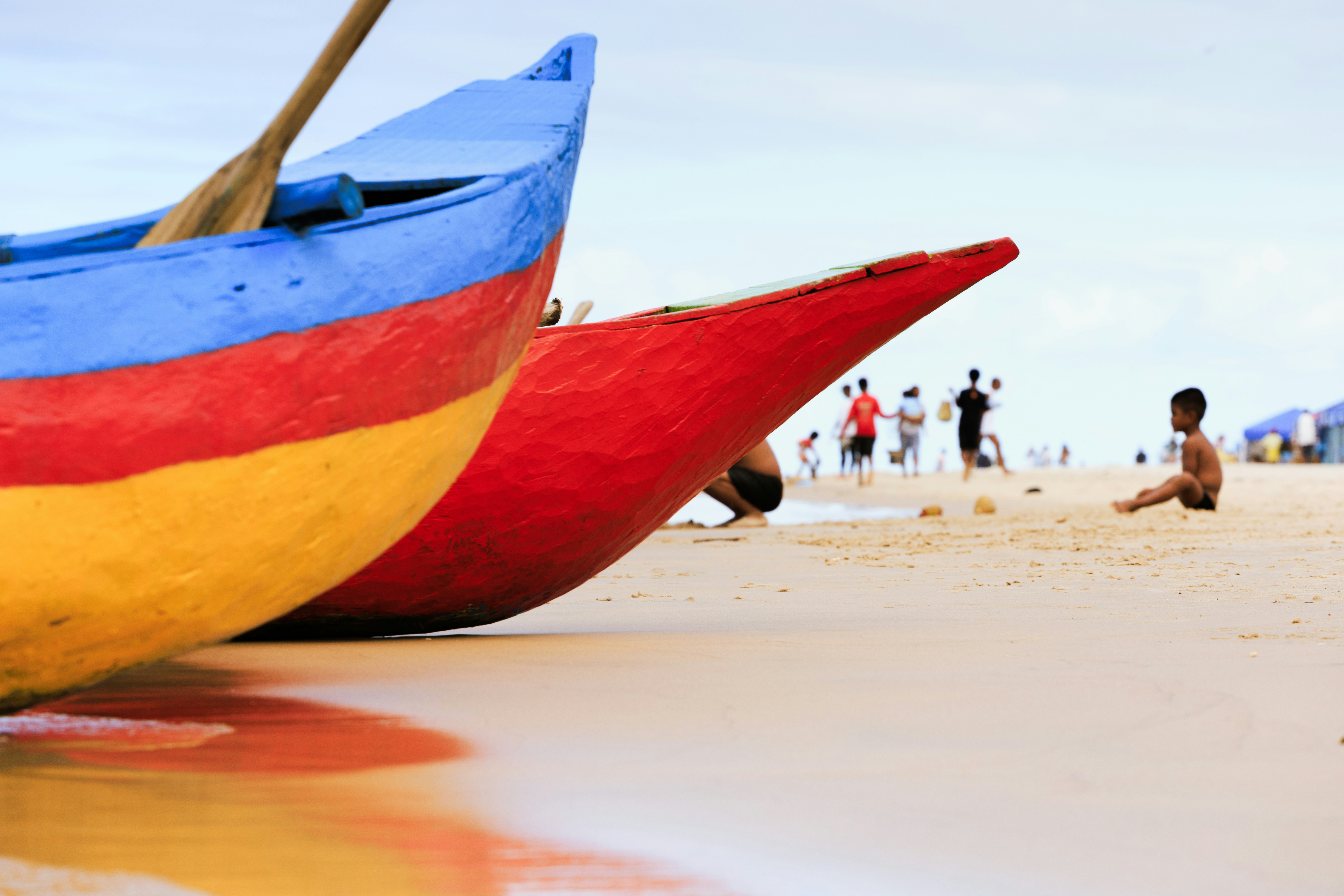 Colorful boats on a sandy beach with people