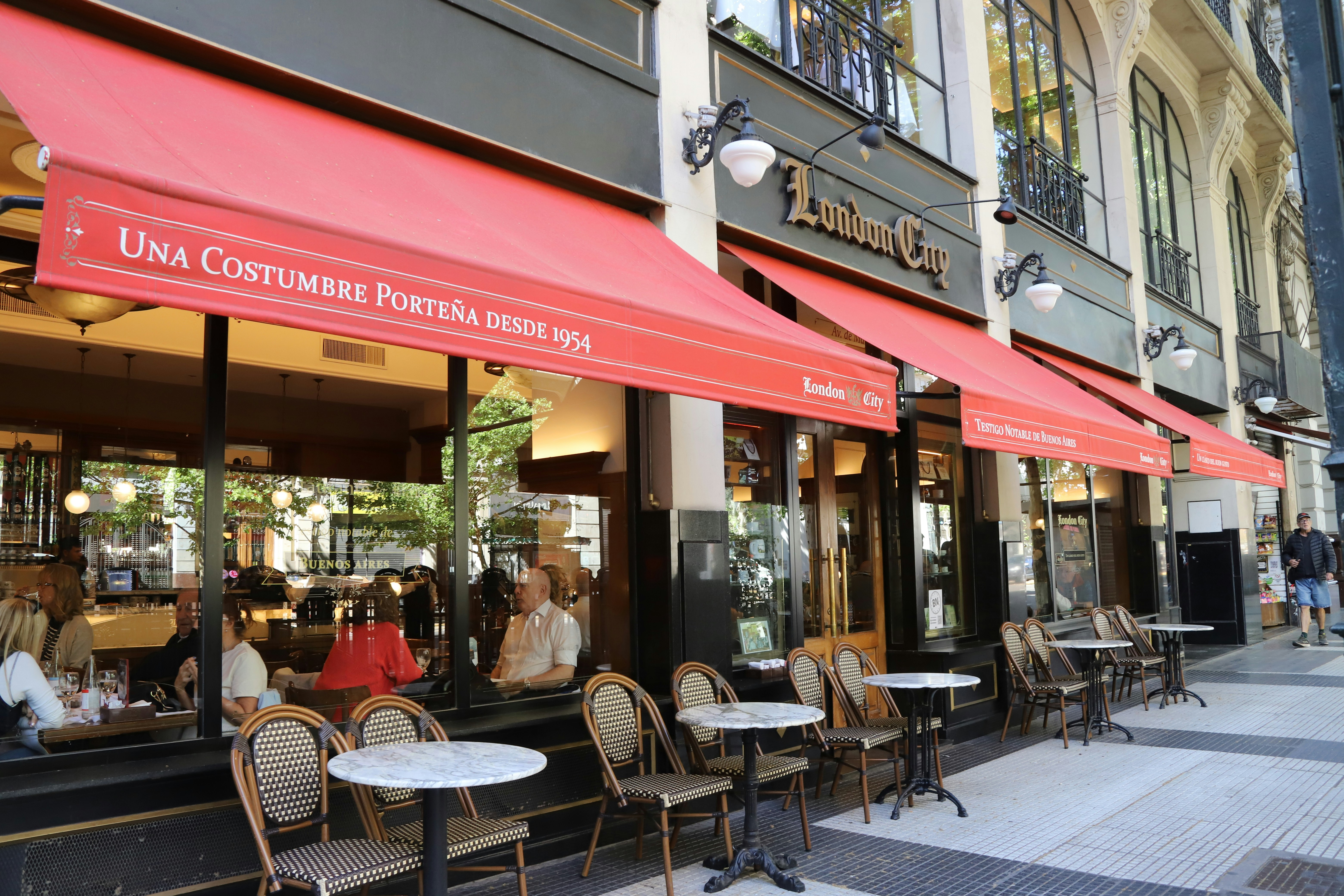 Asientos de cafetería al aire libre con toldos rojos