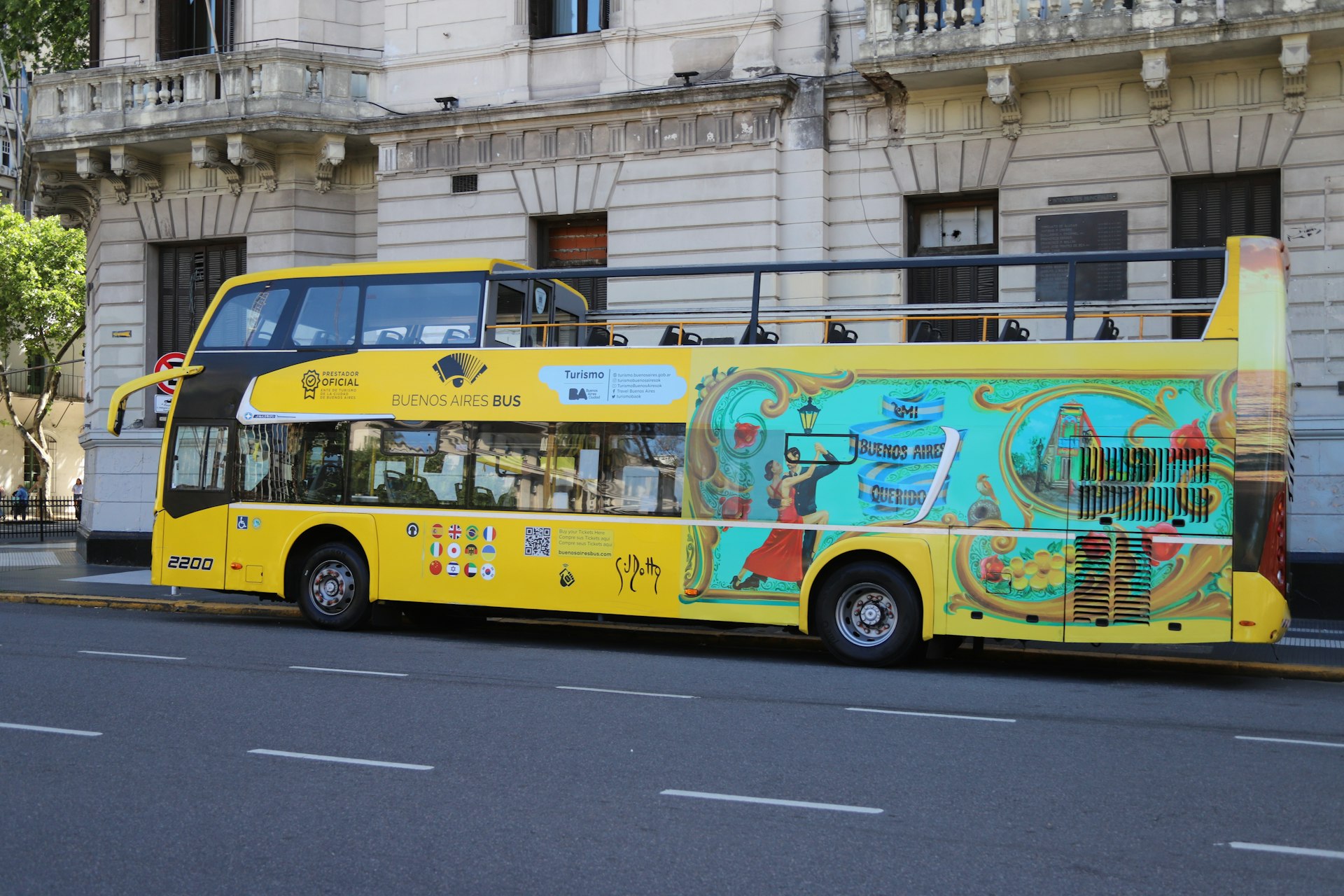 A yellow double-decker bus with colorful murals